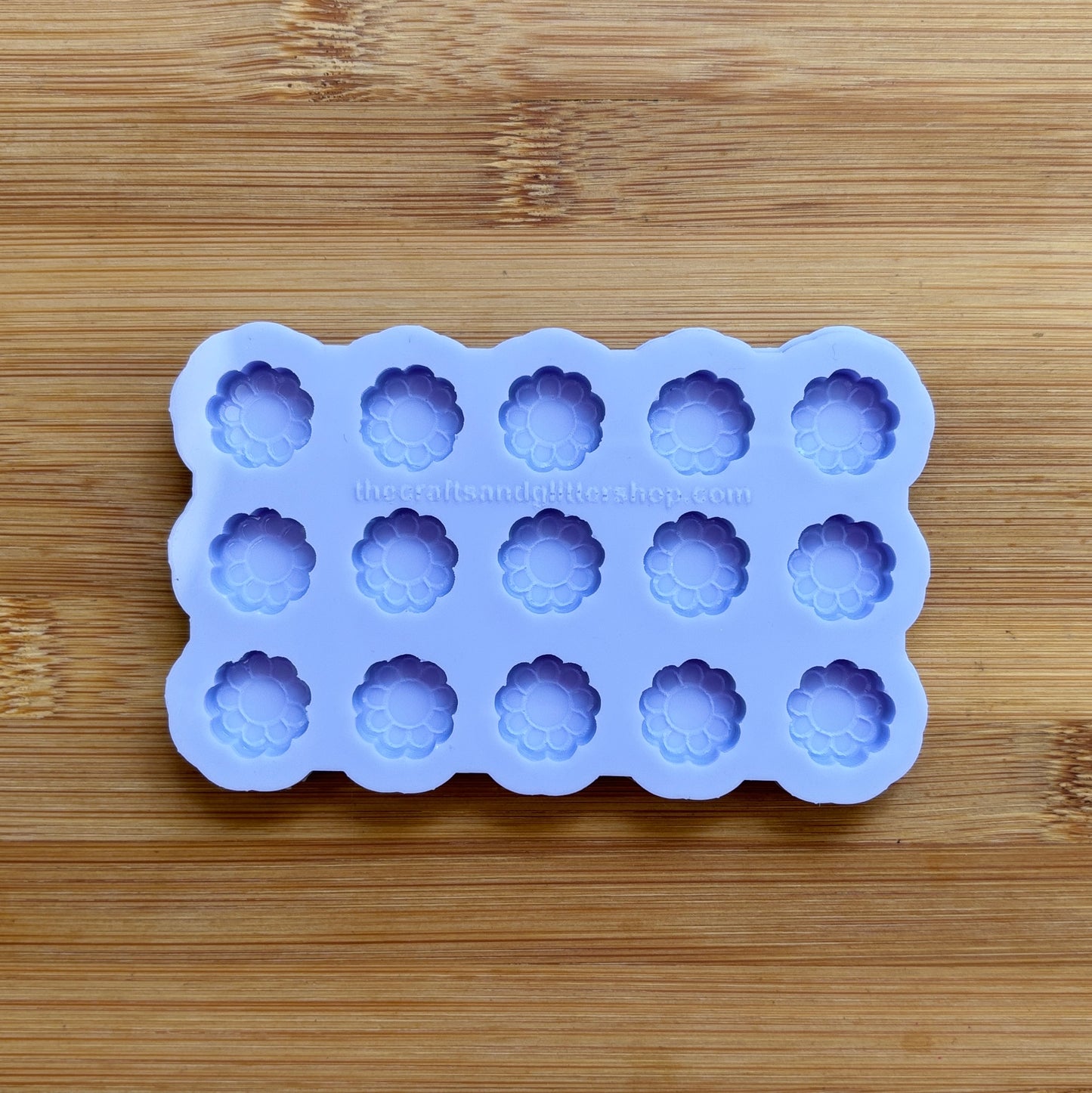 Silicone mold with flower-shaped cavities on a wooden surface