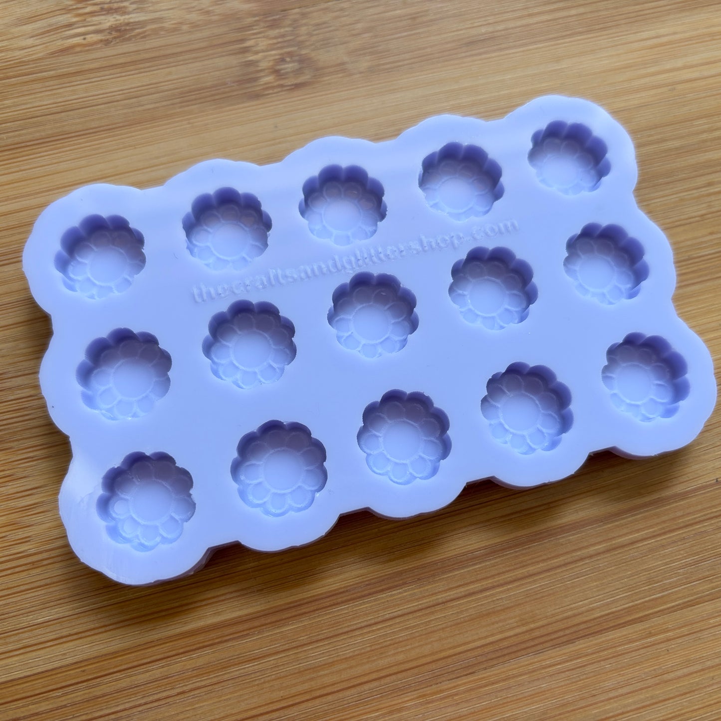 Silicone mold with flower-shaped cavities on a wooden surface
