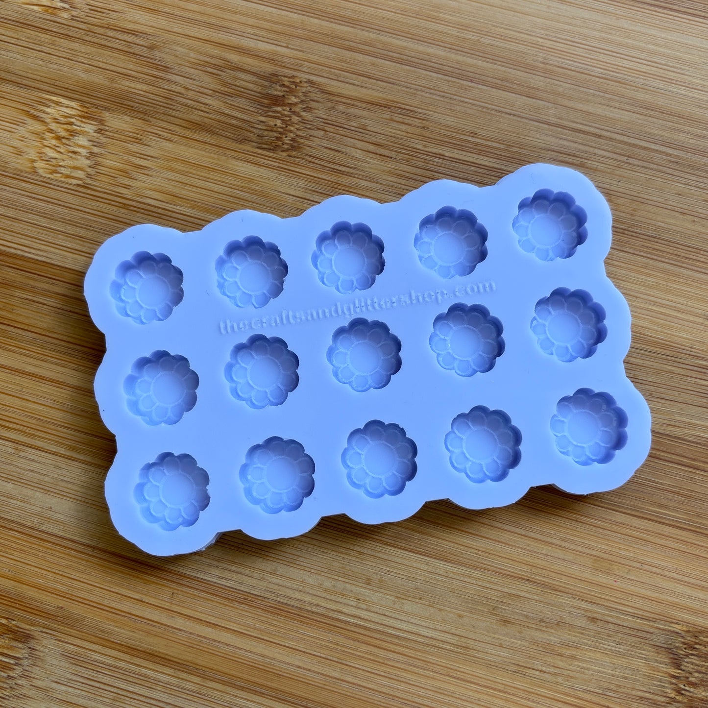 Silicone mold with flower-shaped cavities on a wooden surface