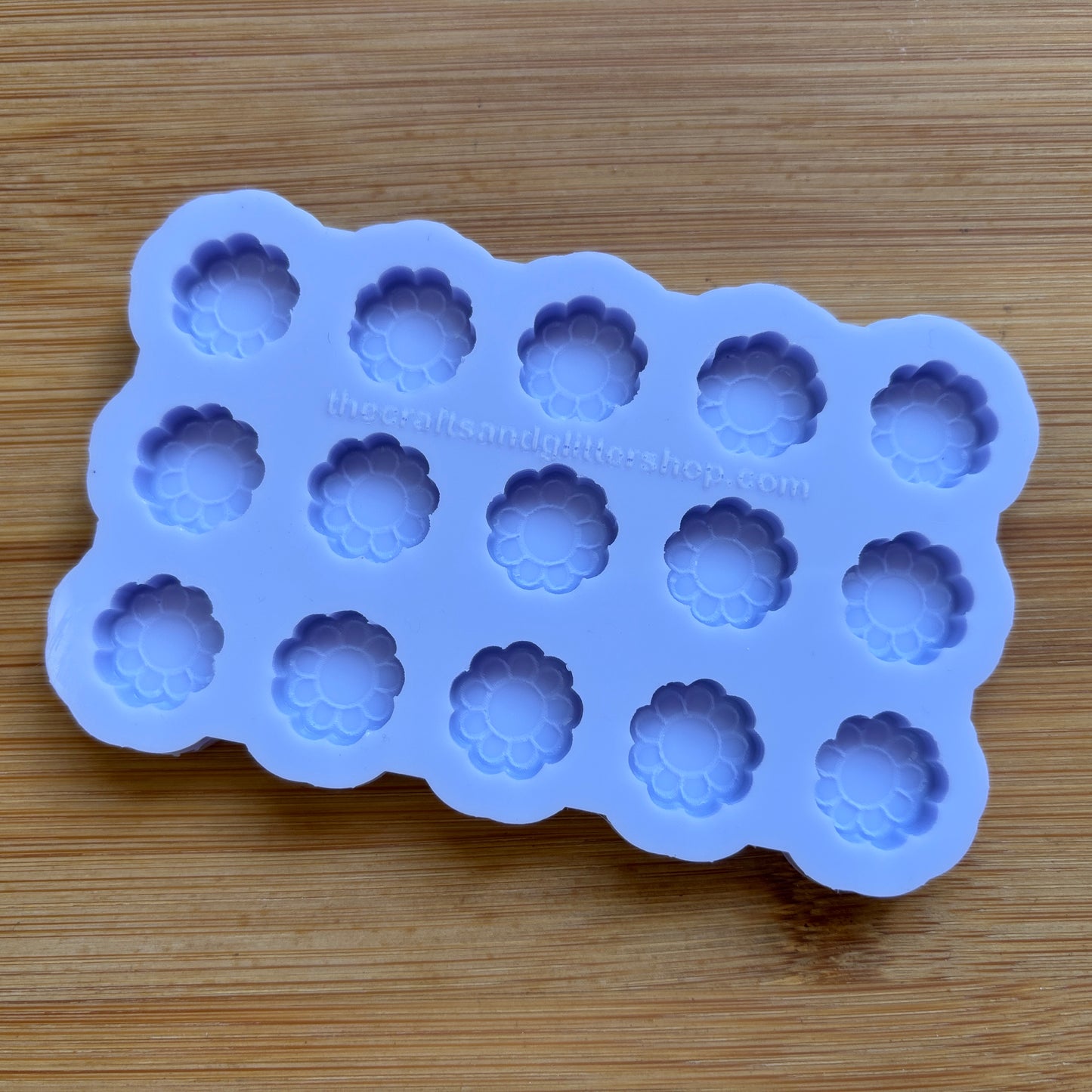 Silicone mold with flower-shaped cavities on a wooden surface