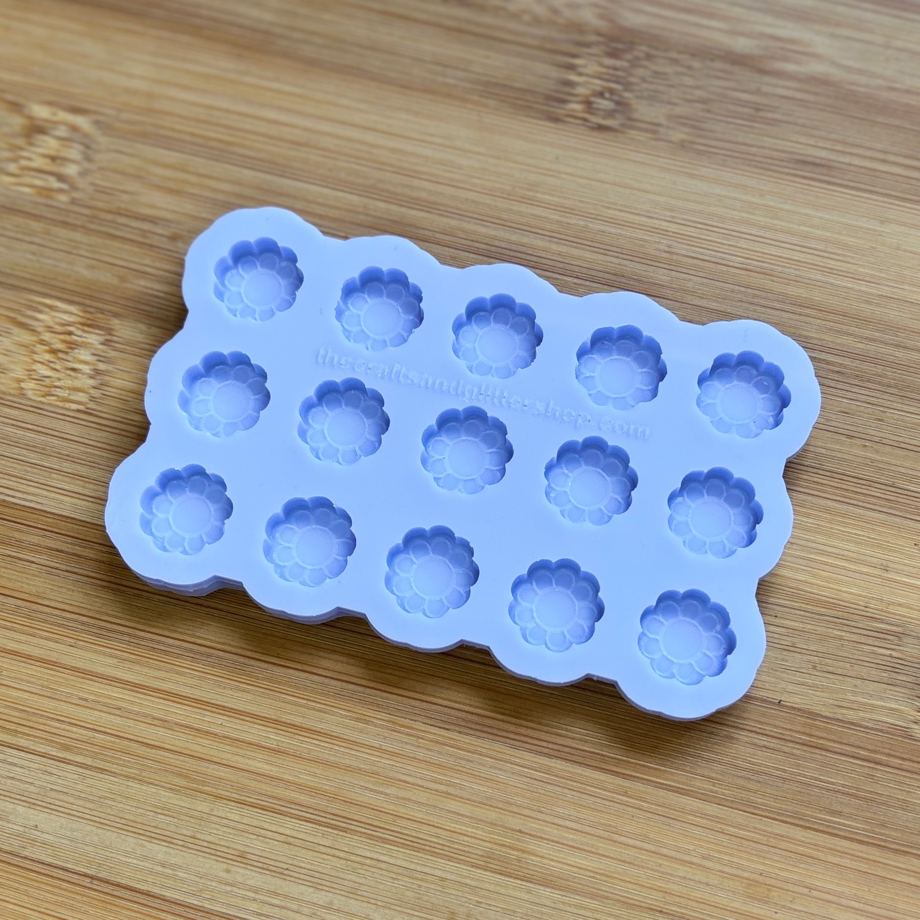 Silicone mold with flower-shaped cavities on a wooden surface
