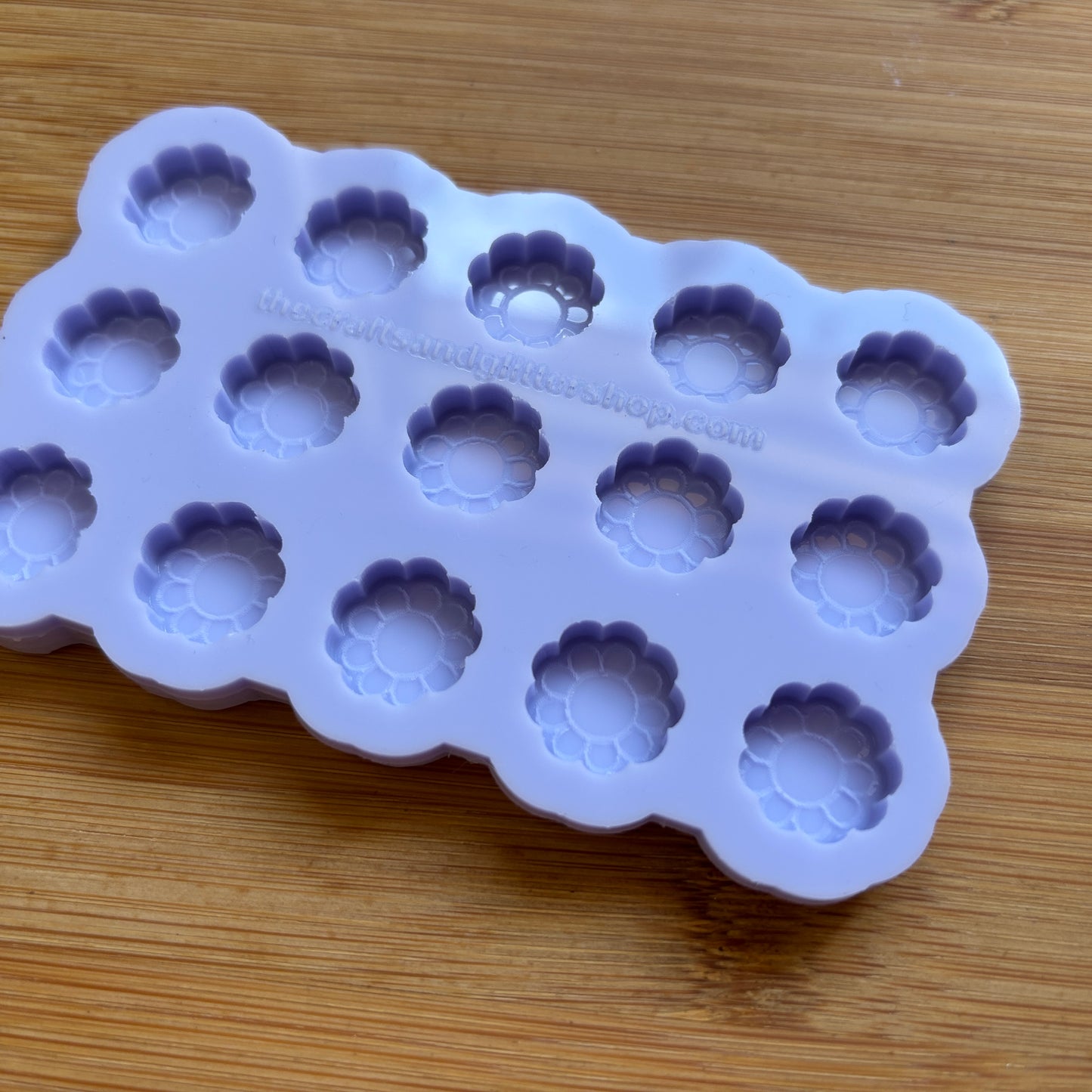 Silicone mold with flower-shaped cavities on a wooden surface
