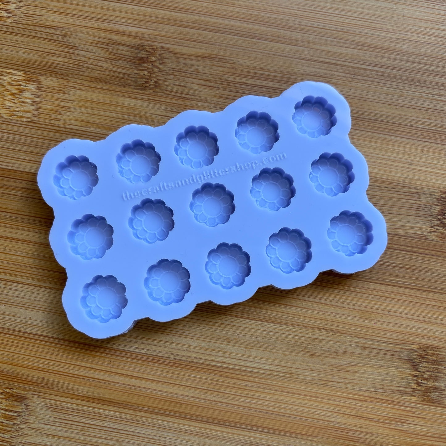 Silicone mold with flower-shaped cavities on a wooden surface