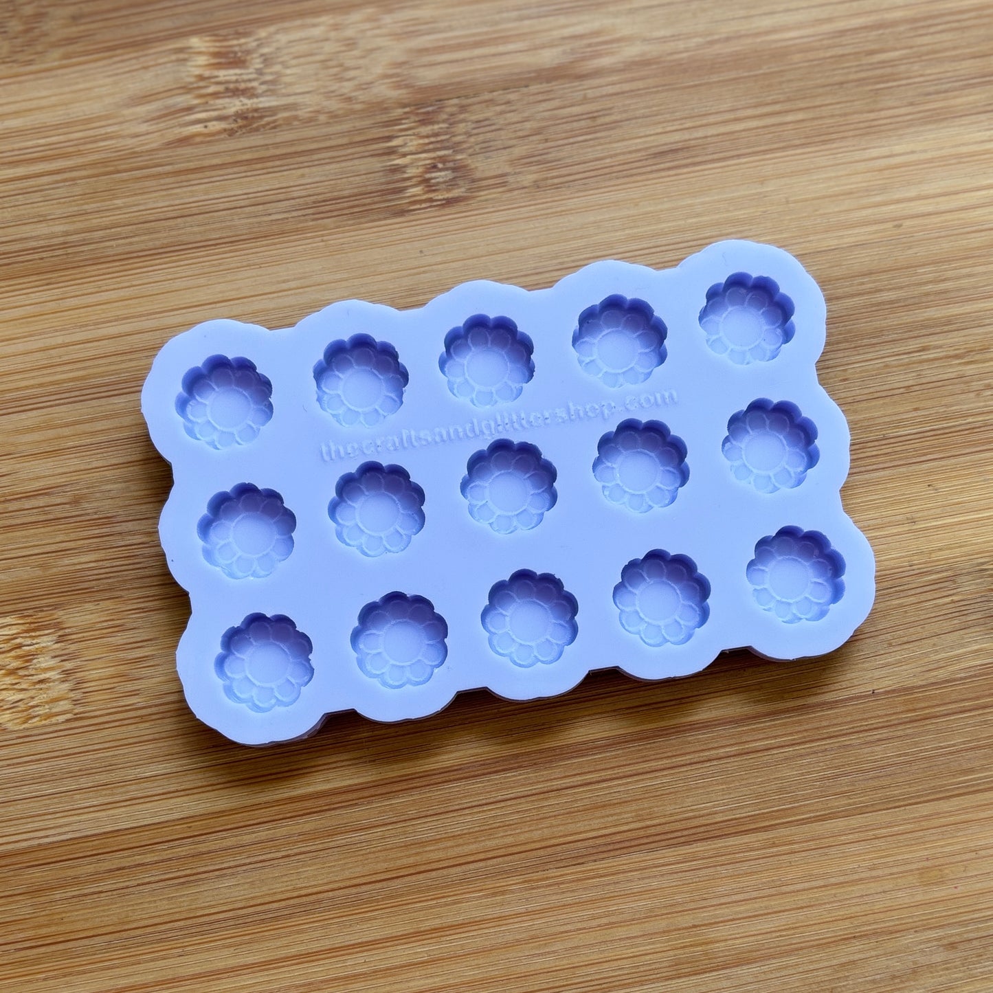 Silicone mold with flower-shaped cavities on a wooden surface
