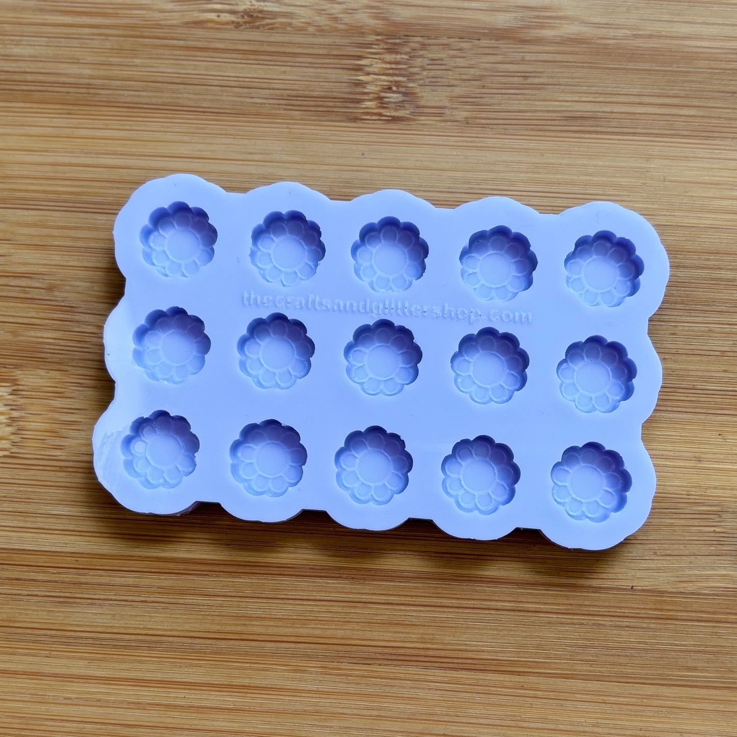 Silicone mold with flower-shaped cavities on a wooden surface
