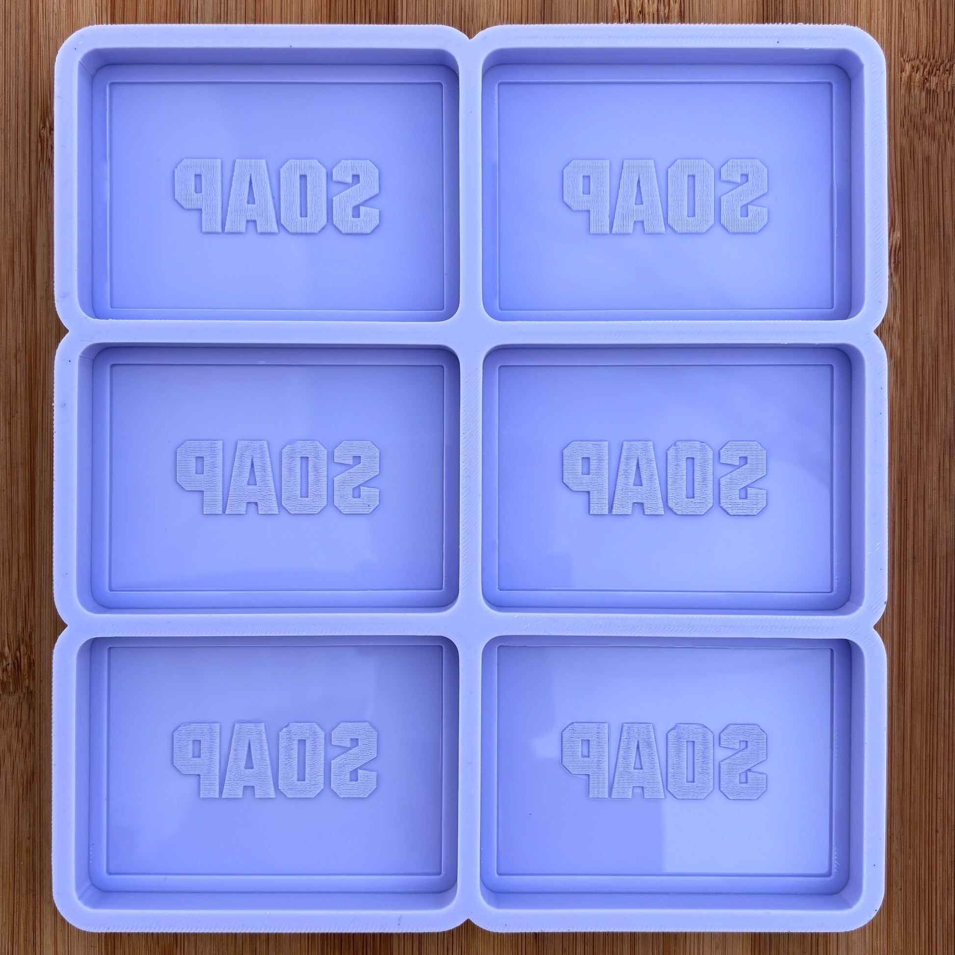 Silicone soap mold with 'SOAP' text on a wooden surface