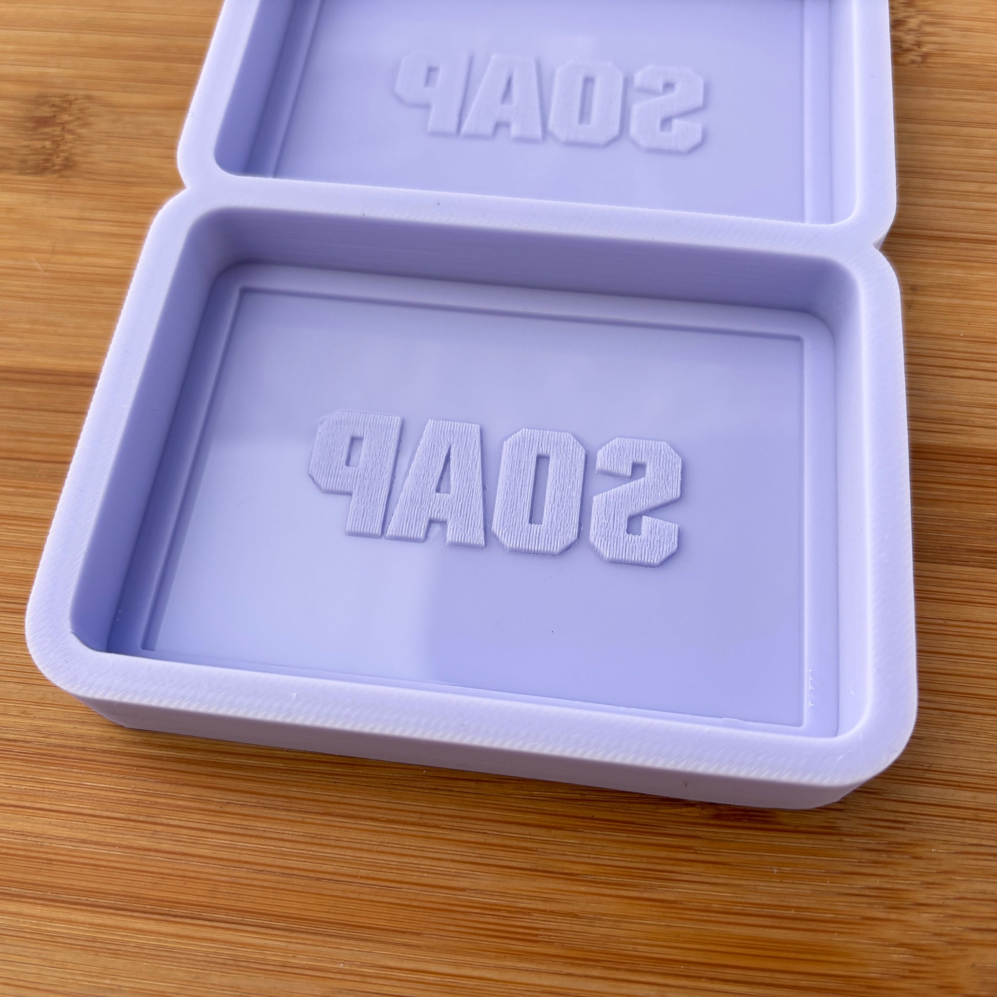 Purple soap mold with 'SOAP' text on a wooden surface