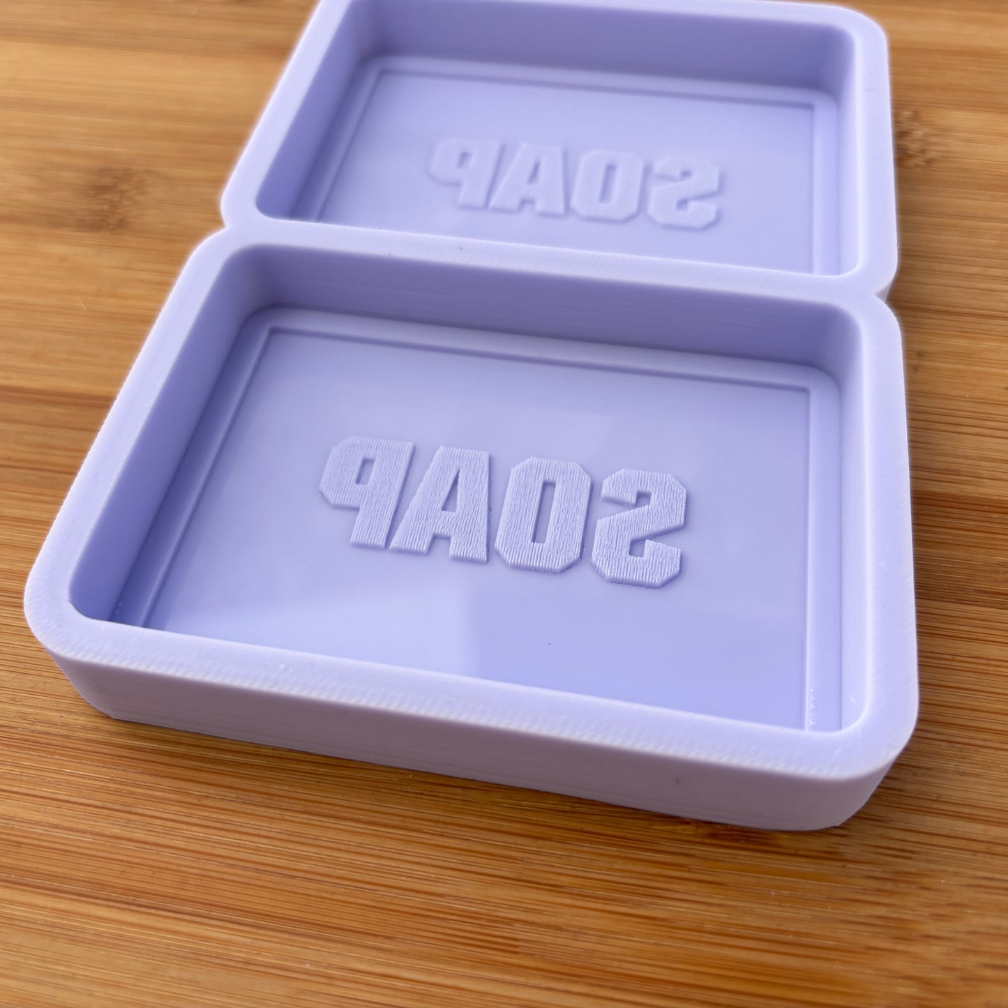 Purple soap mold with 'SOAP' text on a wooden surface