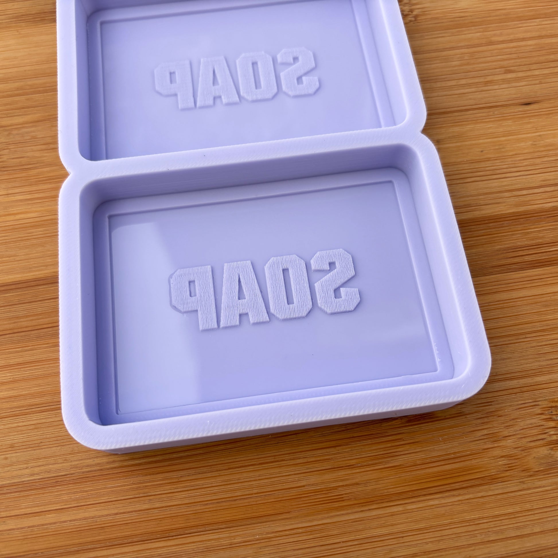 Purple soap mold with 'SOAP' text on a wooden surface