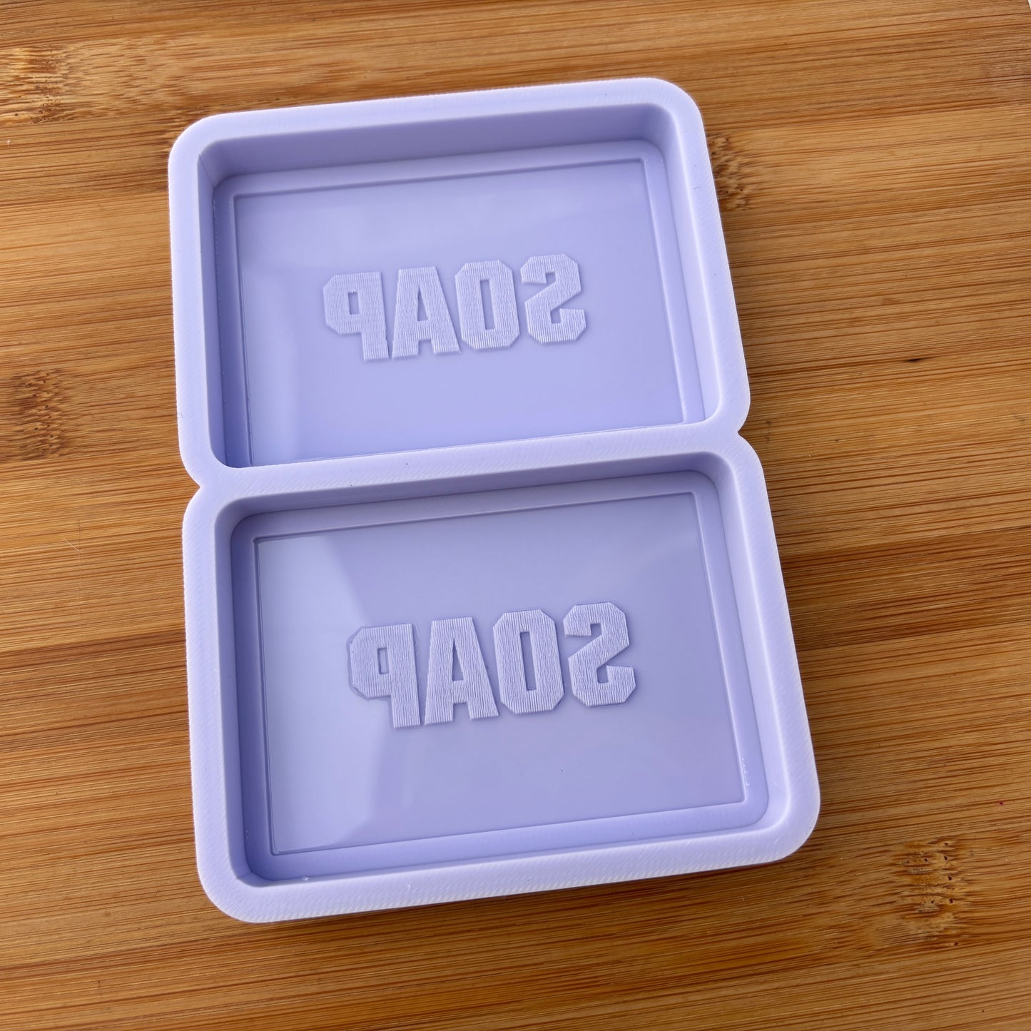 Purple soap mold with 'SOAP' text on a wooden surface
