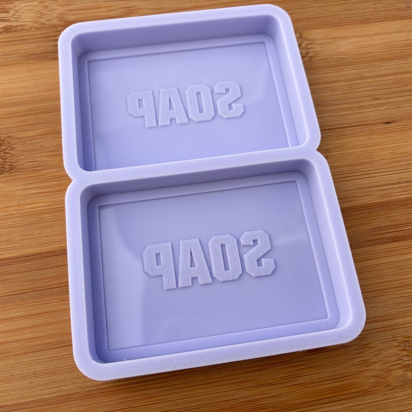 Purple soap mold with 'SOAP' text on a wooden surface