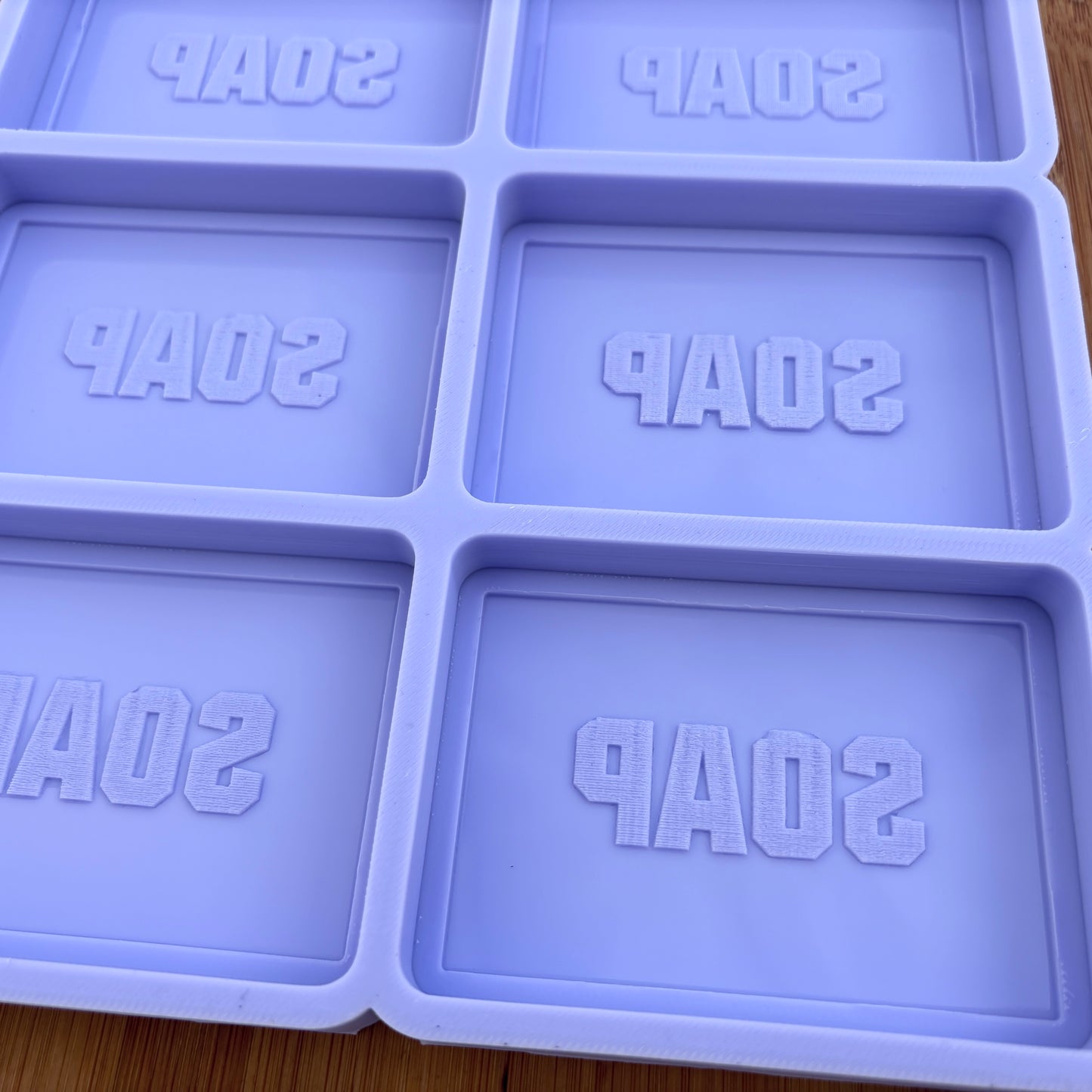 Purple soap mold with 'SOAP' text on a wooden surface