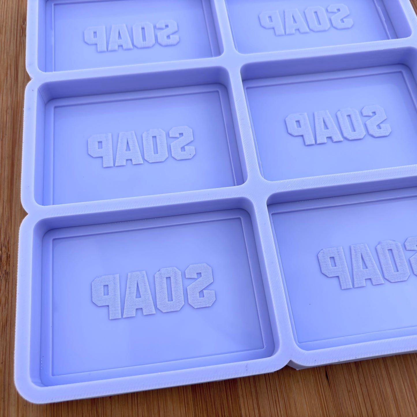 Silicone soap mold with 'SOAP' text on a wooden surface