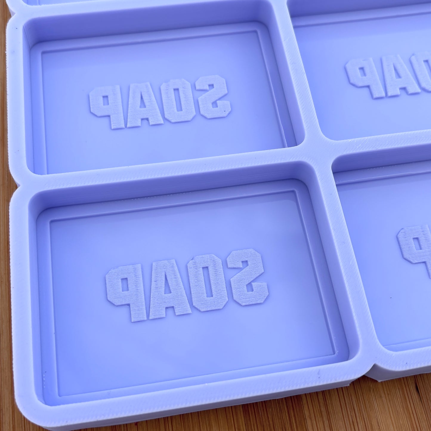 Purple soap mold with 'SOAP' text on a wooden surface