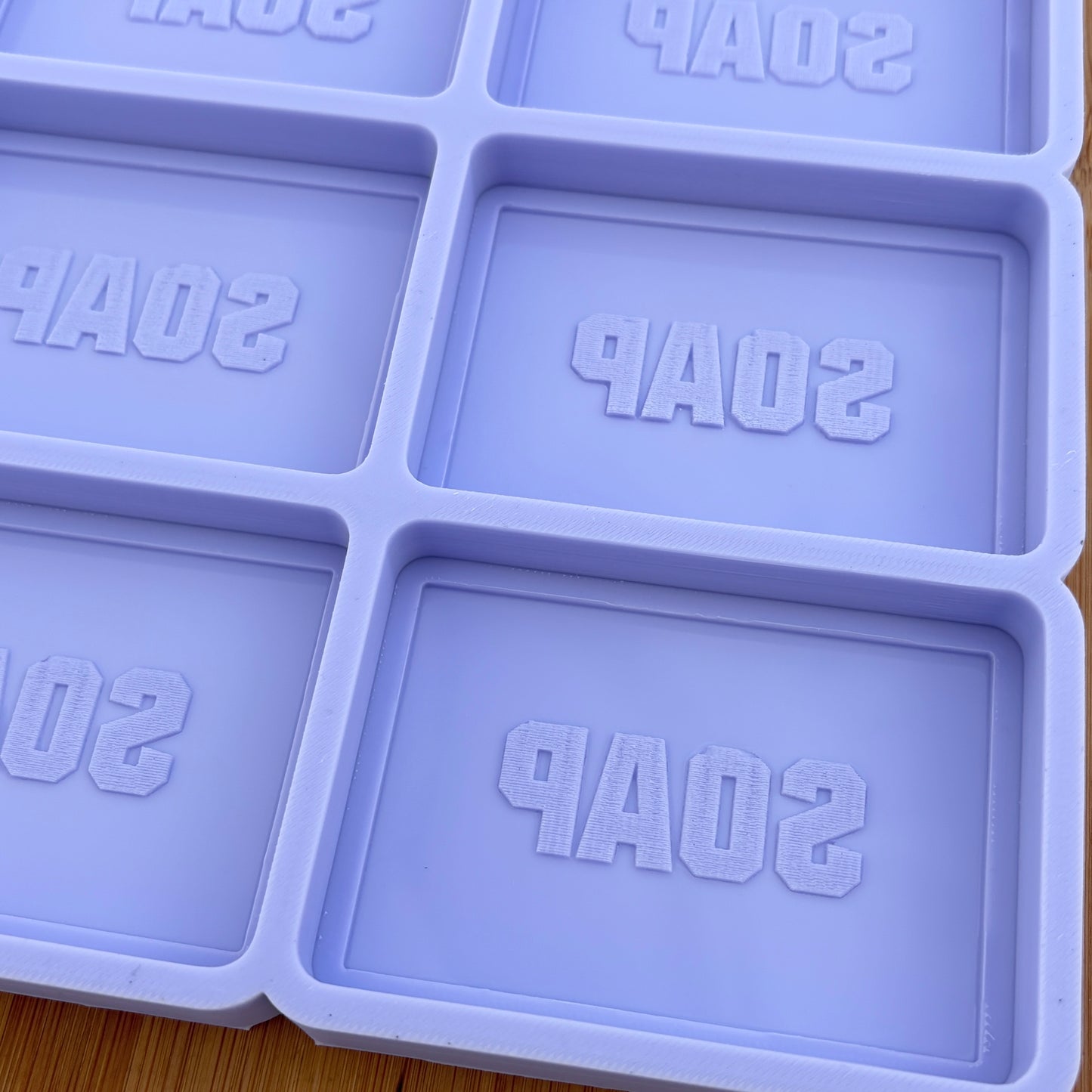 Purple soap mold with 'SOAP' text on a wooden surface