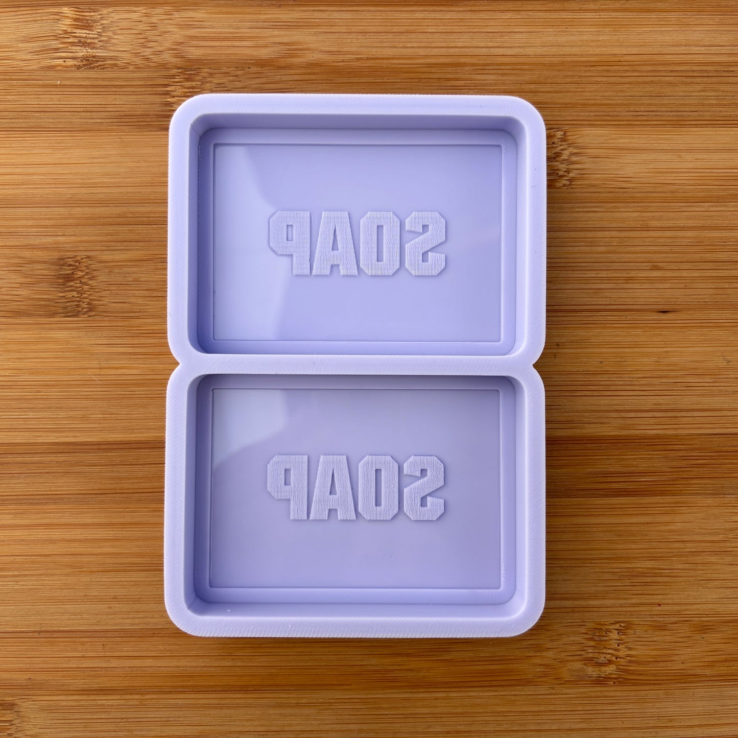 Purple soap mold with 'SOAP' text on a wooden surface