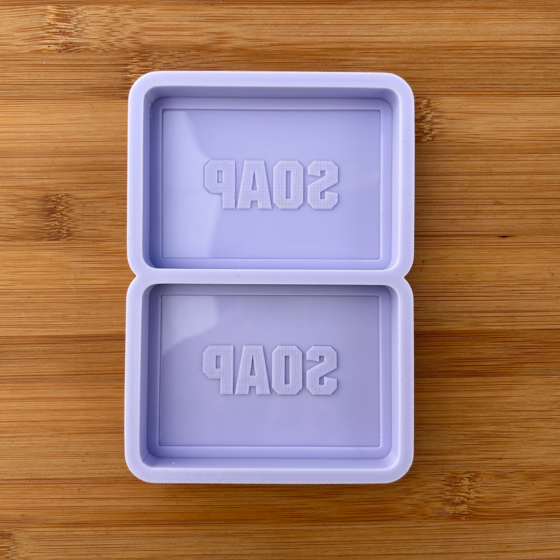 Purple soap mold with 'SOAP' text on a wooden surface
