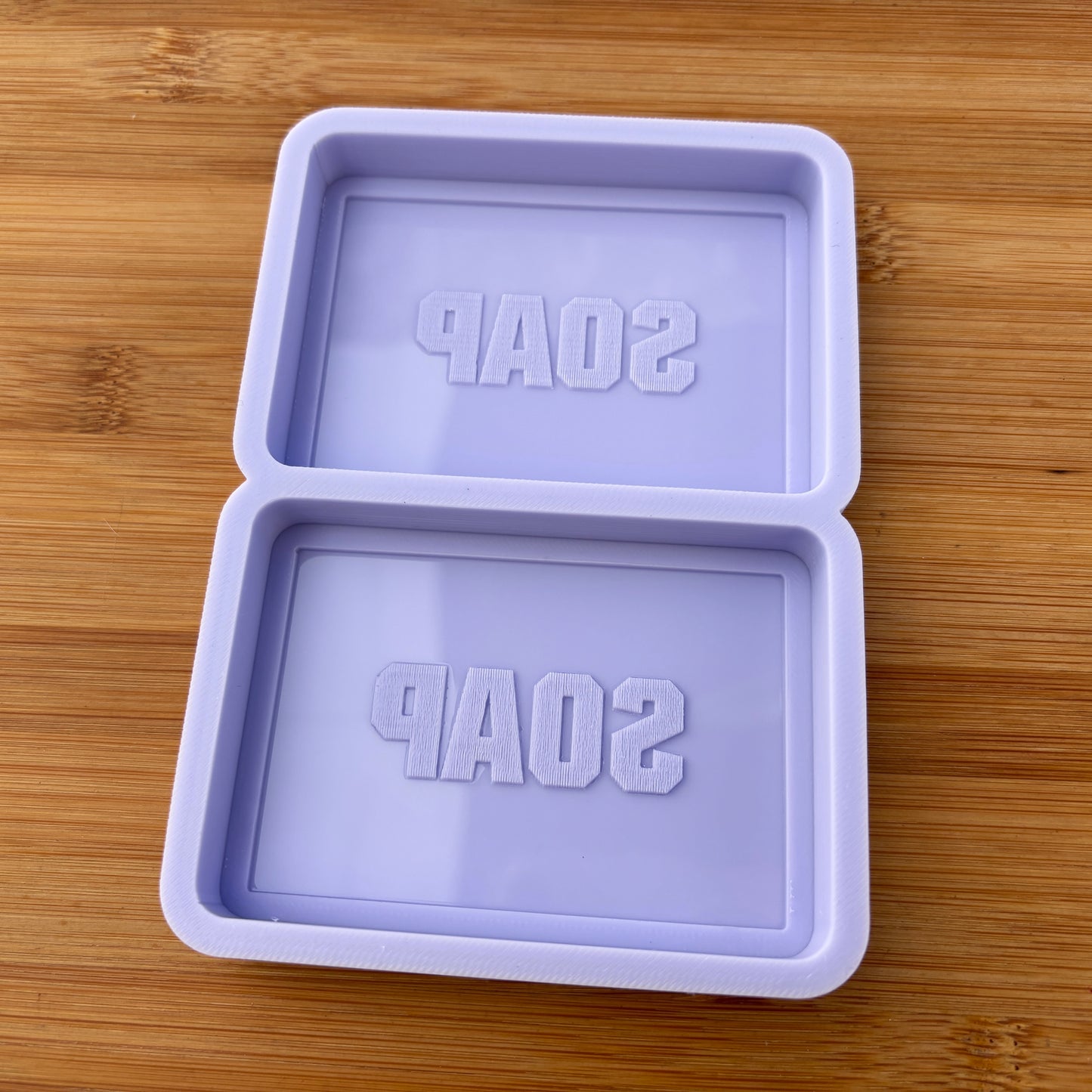 Purple soap mold with 'SOAP' text on a wooden surface