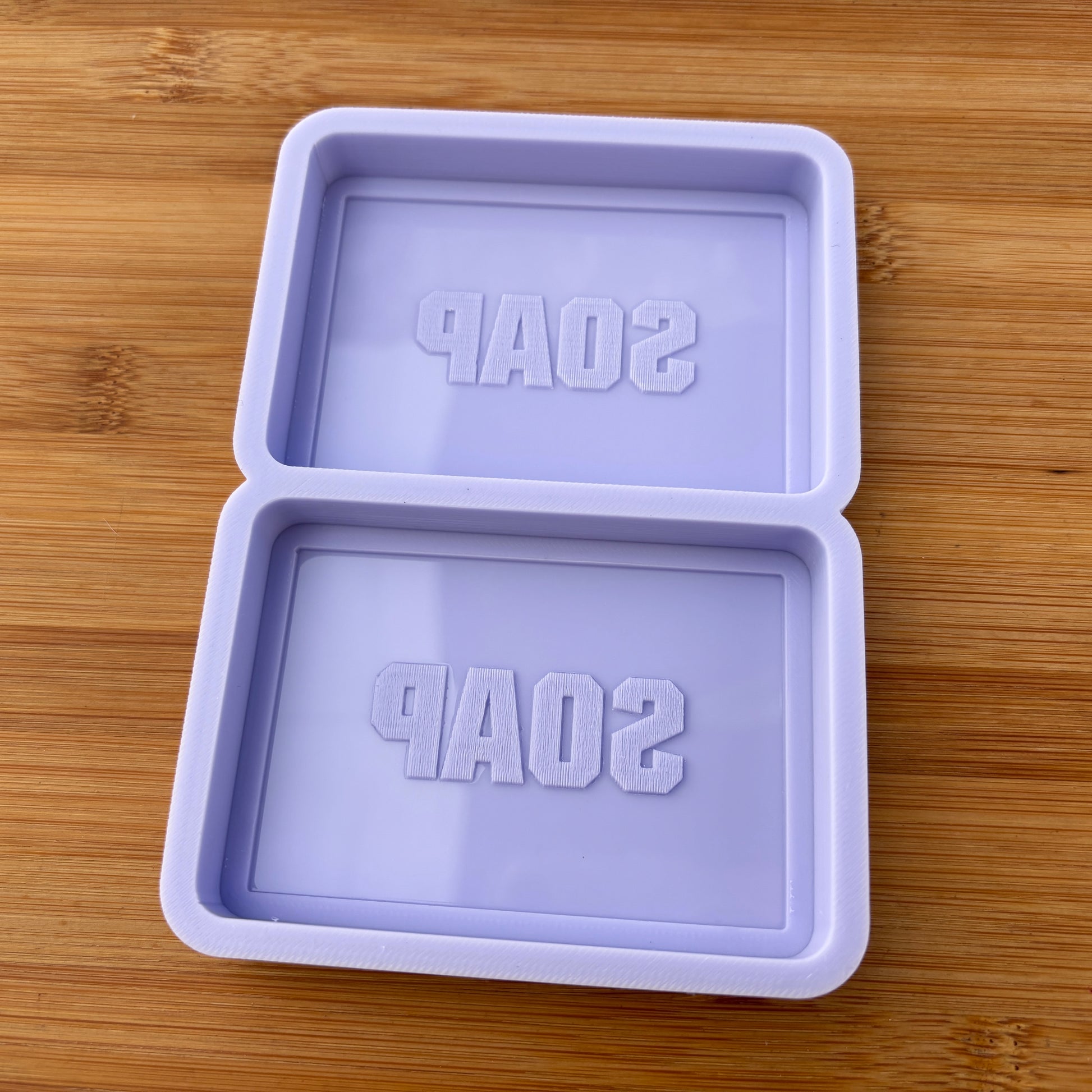 Purple soap mold with 'SOAP' text on a wooden surface