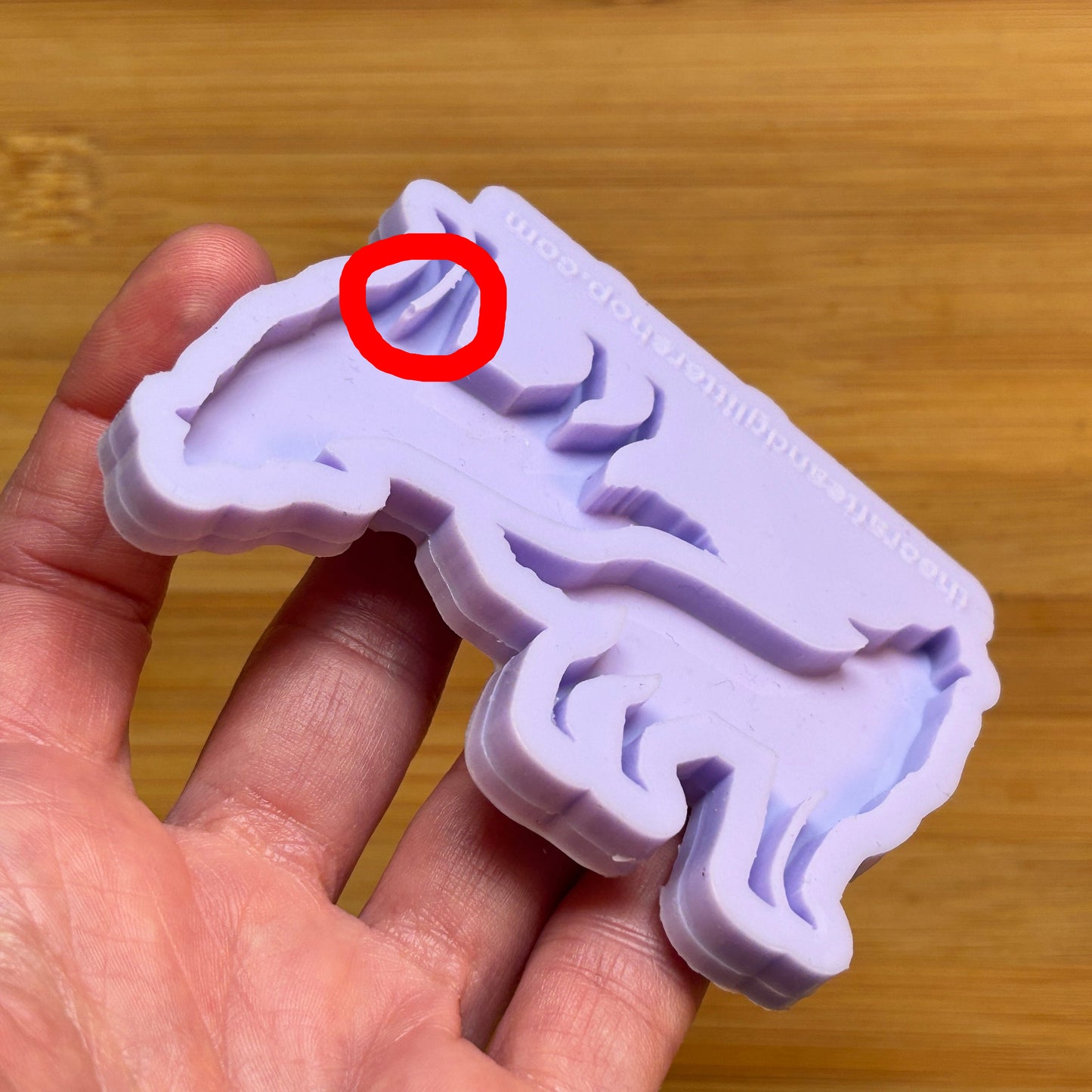 Silicone mold shaped like a wolf held in a hand on a wooden surface