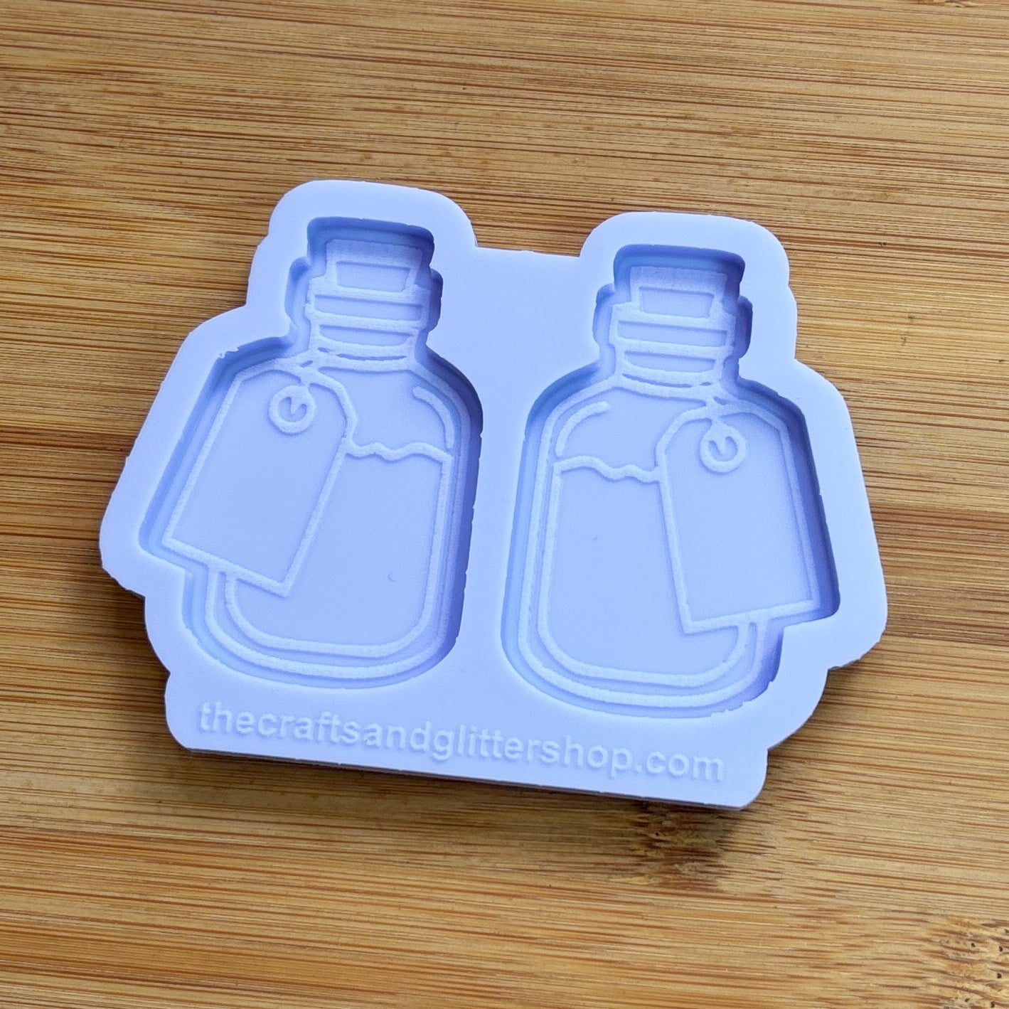 Silicone mold shaped like bottles with a label on a wooden surface