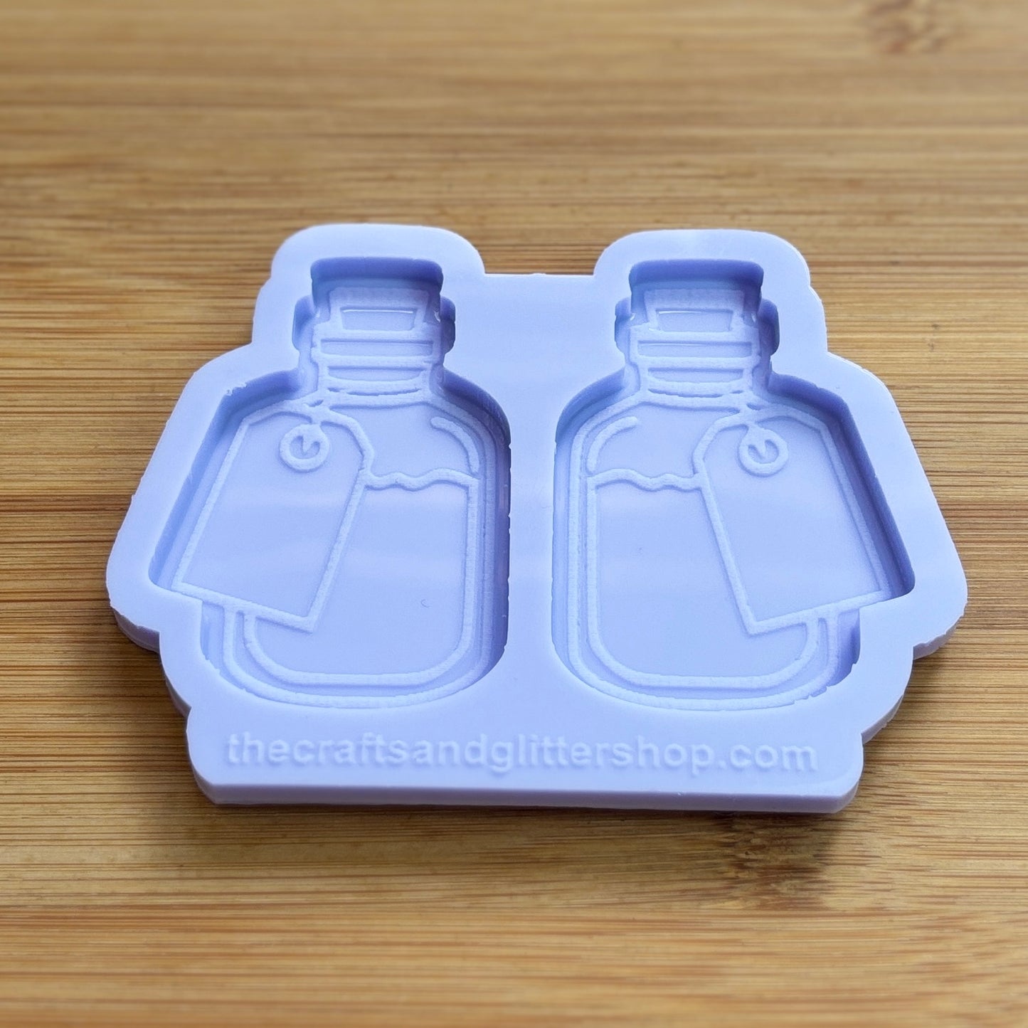 Silicone mold shaped like bottles on a wooden surface with 'thecraftsandglittershop.com' branding.