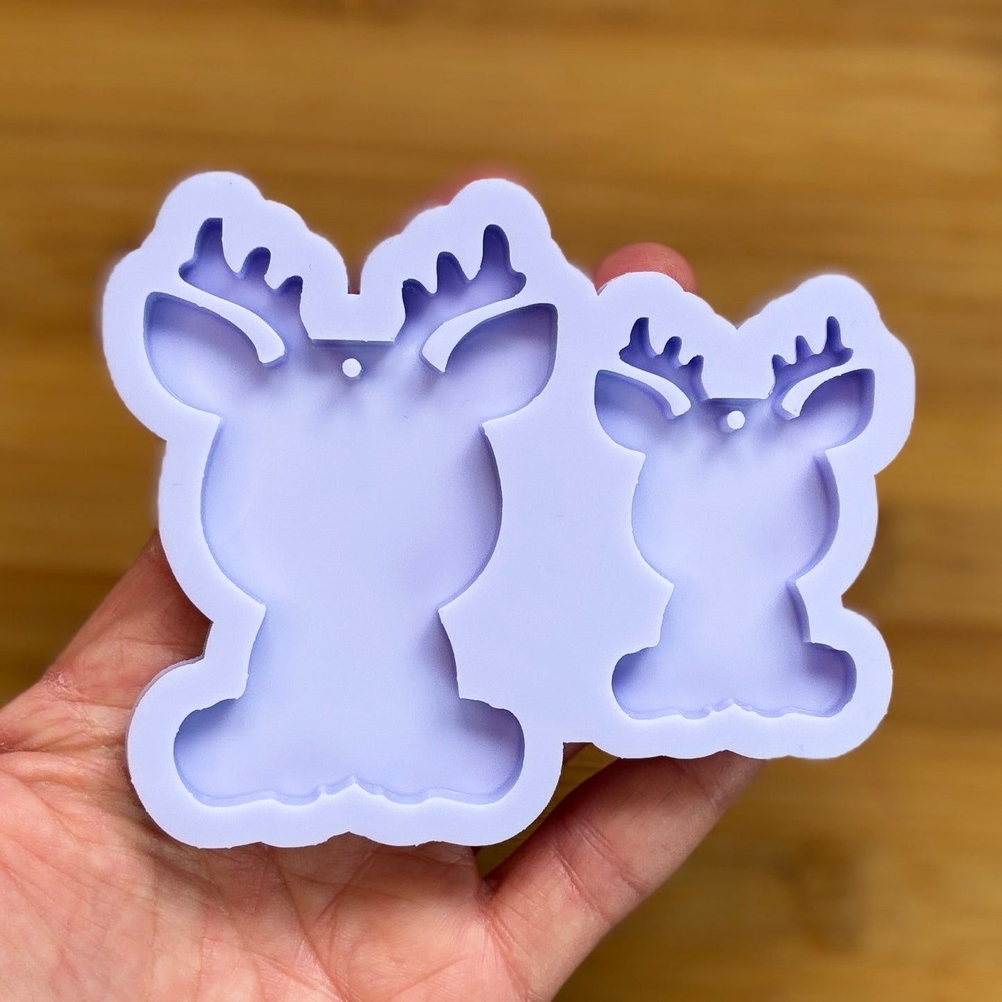 Reindeer silhouette Silicone Mold with 2 cavities of different sizes. The cavity has a hole in it. The mols is made with Food Safe Silicone suitable for both food and craft projects.