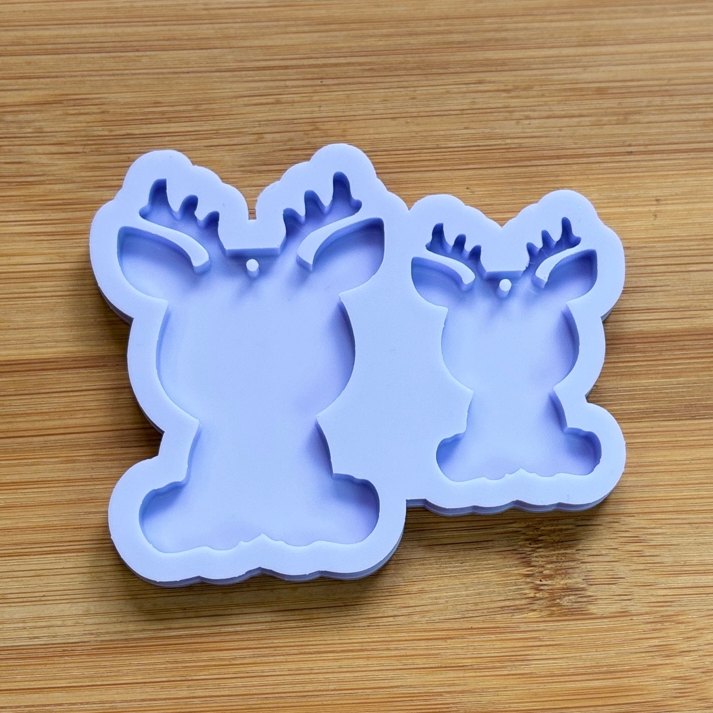 Reindeer silhouette Silicone Mold with 2 cavities of different sizes. The cavity has a hole in it. The mols is made with Food Safe Silicone suitable for both food and craft projects.