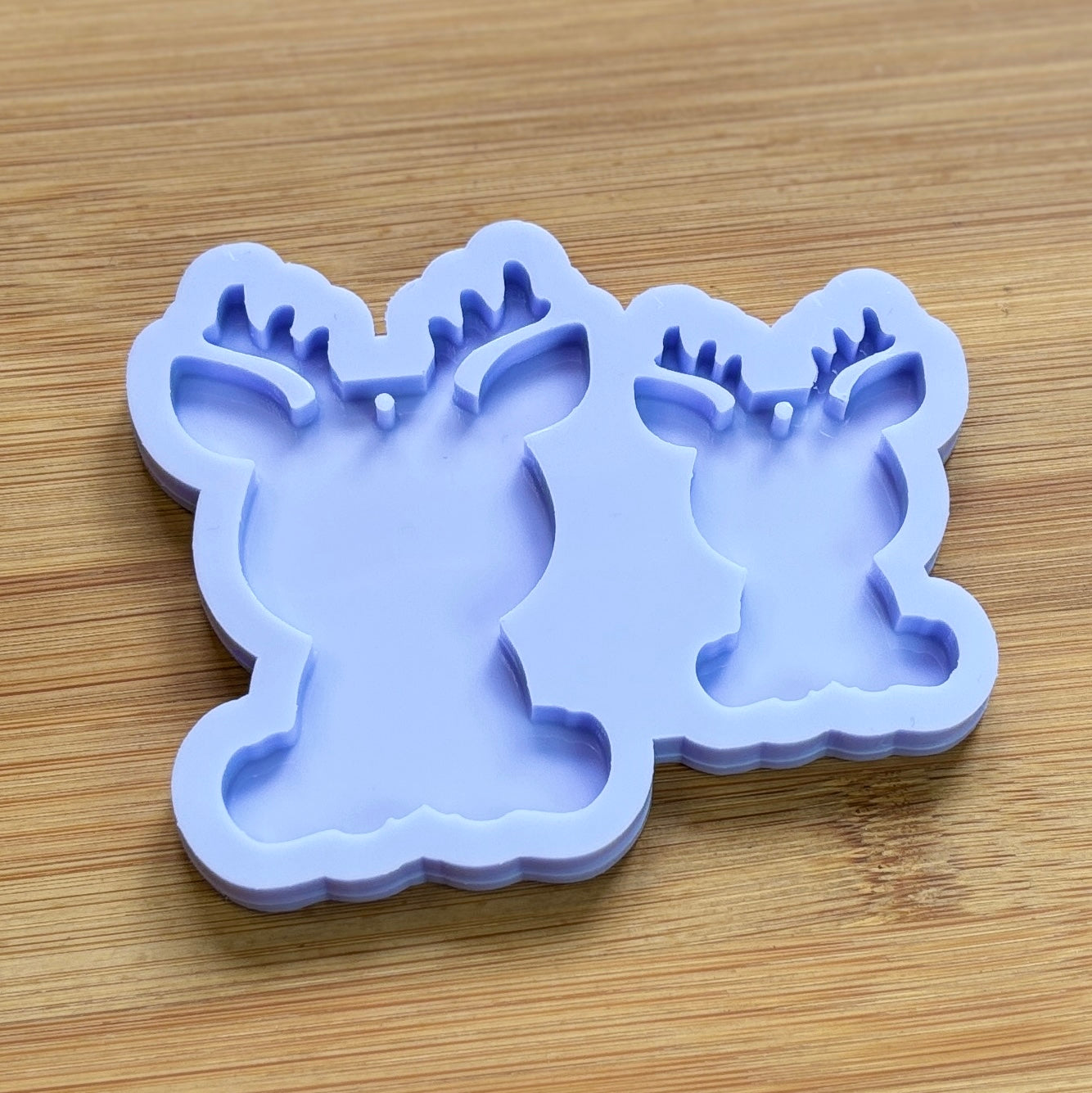 Reindeer silhouette Silicone Mold with 2 cavities of different sizes. The cavity has a hole in it. The mols is made with Food Safe Silicone suitable for both food and craft projects.
