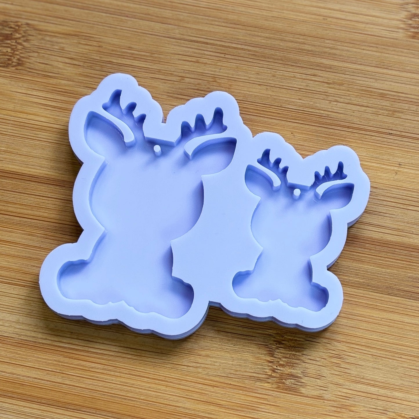 Reindeer silhouette Silicone Mold with 2 cavities of different sizes. The cavity has a hole in it. The mols is made with Food Safe Silicone suitable for both food and craft projects.