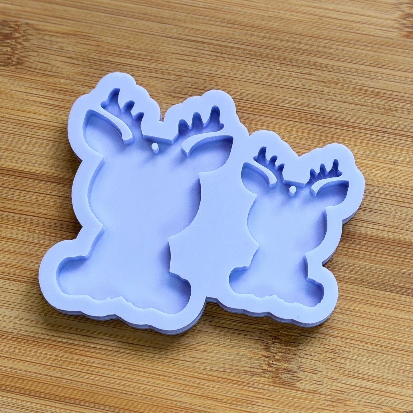 Reindeer silhouette Silicone Mold with 2 cavities of different sizes. The cavity has a hole in it. The mols is made with Food Safe Silicone suitable for both food and craft projects.