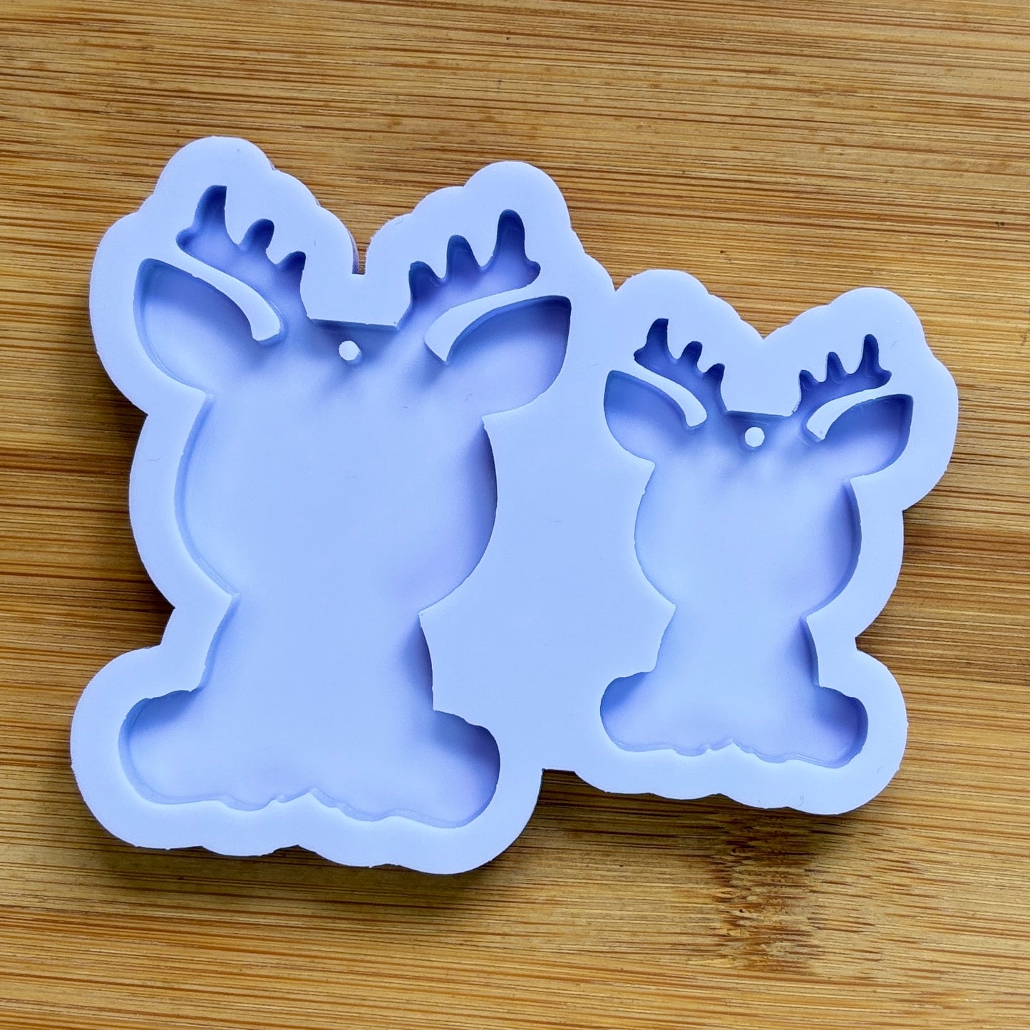 Reindeer silhouette Silicone Mold with 2 cavities of different sizes. The cavity has a hole in it. The mols is made with Food Safe Silicone suitable for both food and craft projects.