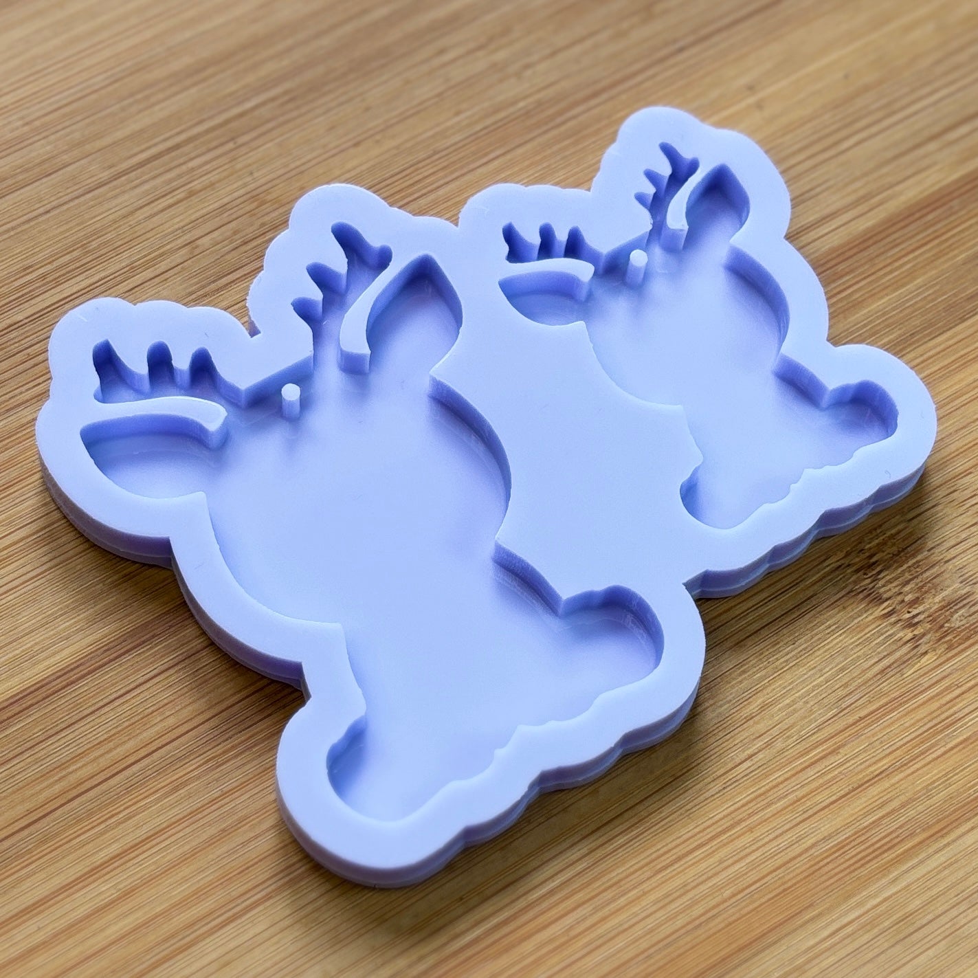 Reindeer silhouette Silicone Mold with 2 cavities of different sizes. The cavity has a hole in it. The mols is made with Food Safe Silicone suitable for both food and craft projects.