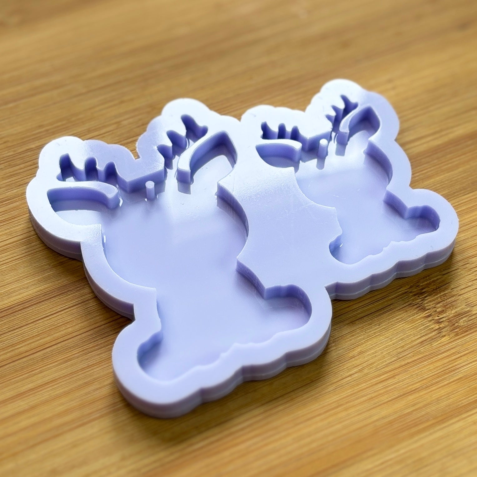 Reindeer silhouette Silicone Mold with 2 cavities of different sizes. The cavity has a hole in it. The mols is made with Food Safe Silicone suitable for both food and craft projects.