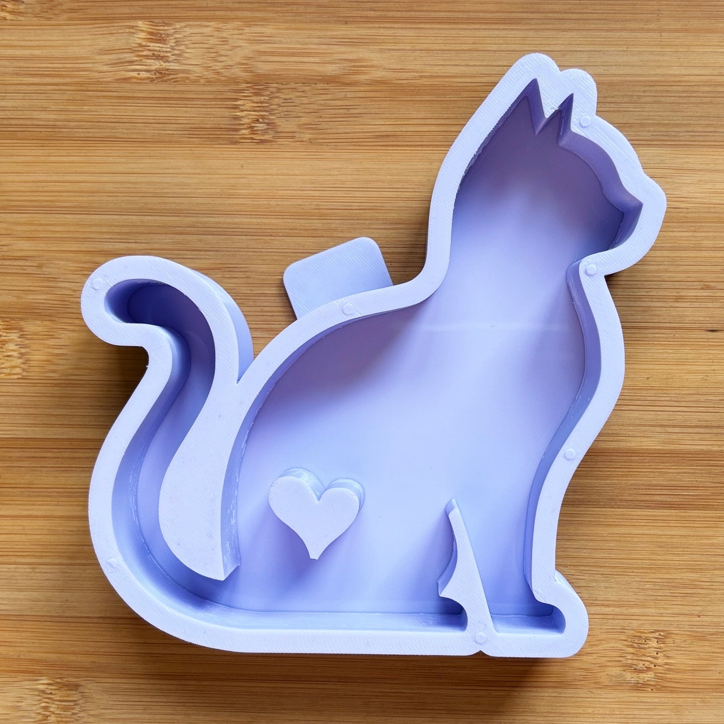Silicone mold shaped like a cat with a heart on a wooden surface