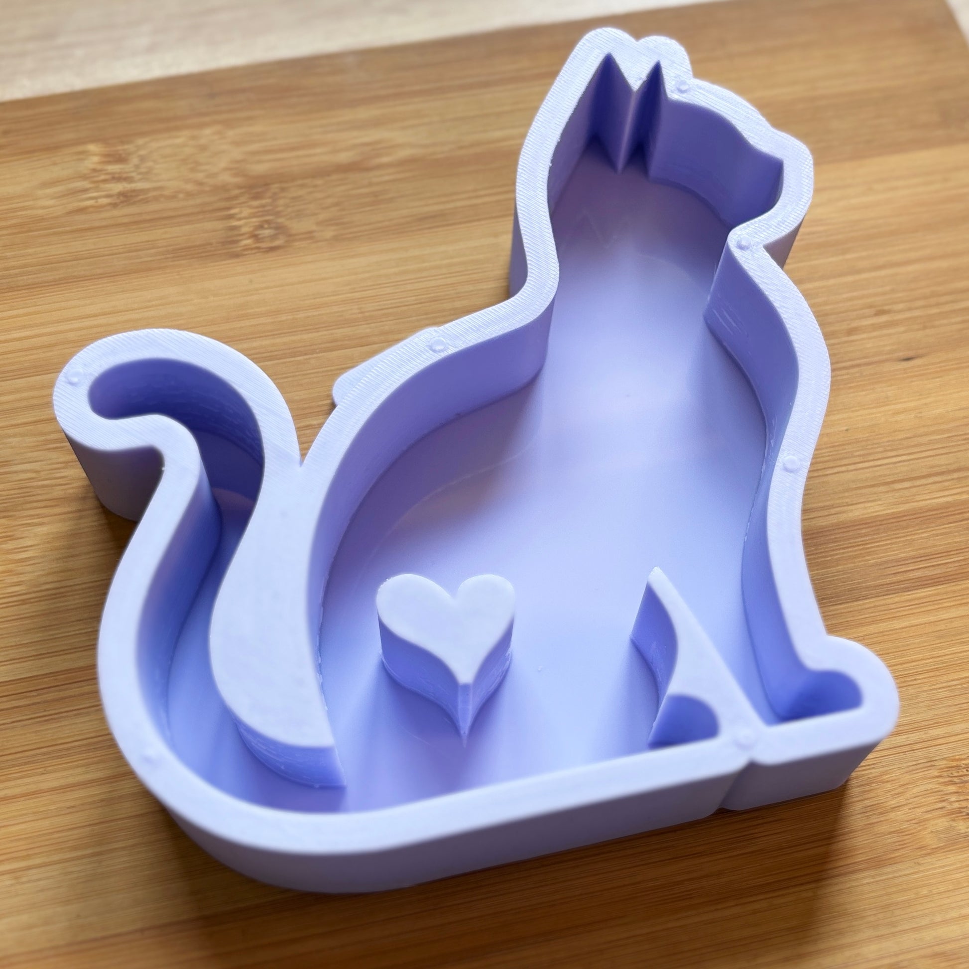 Purple silicone mold shaped like a cat with a heart on a wooden surface