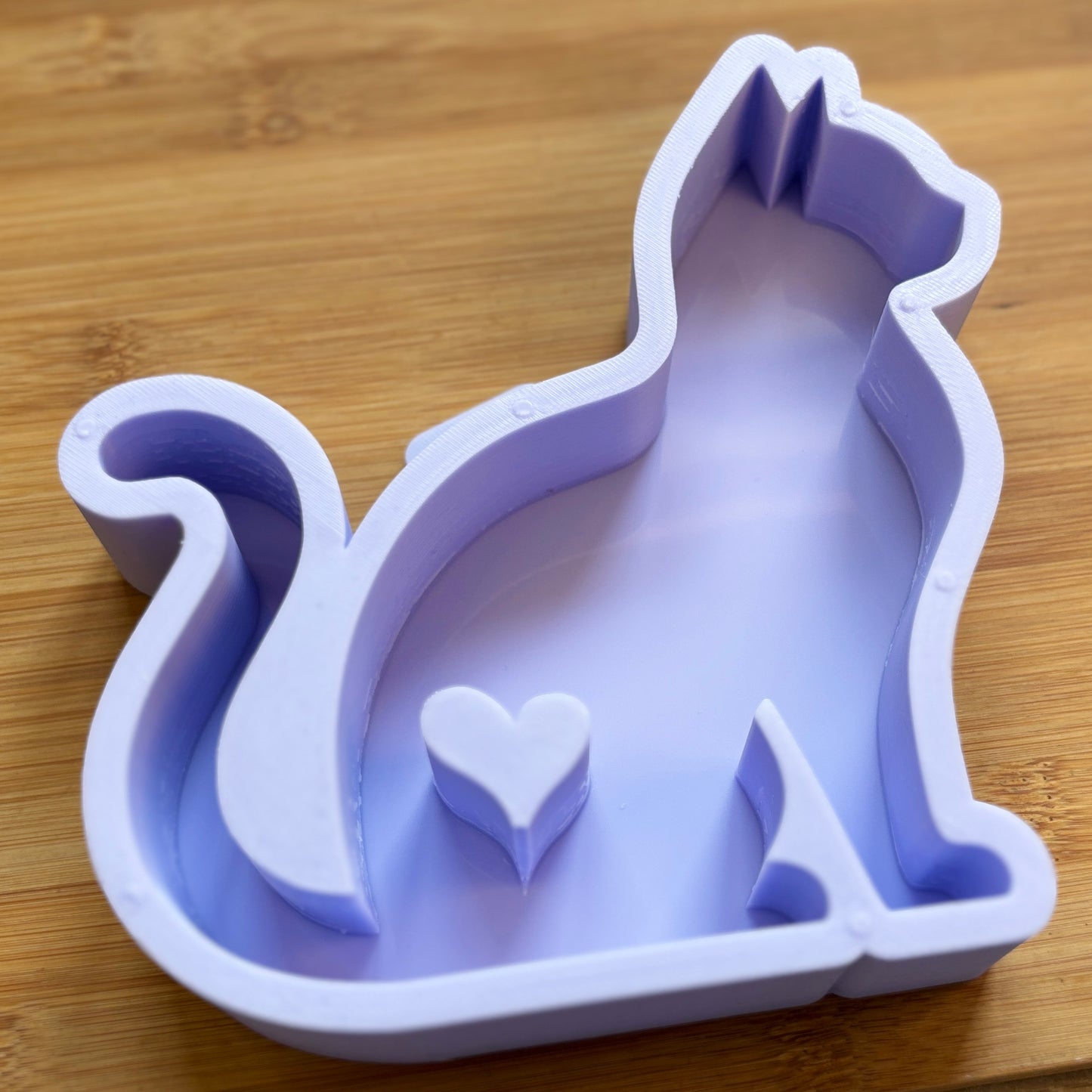 Silicone mold shaped like a cat with a heart on a wooden surface