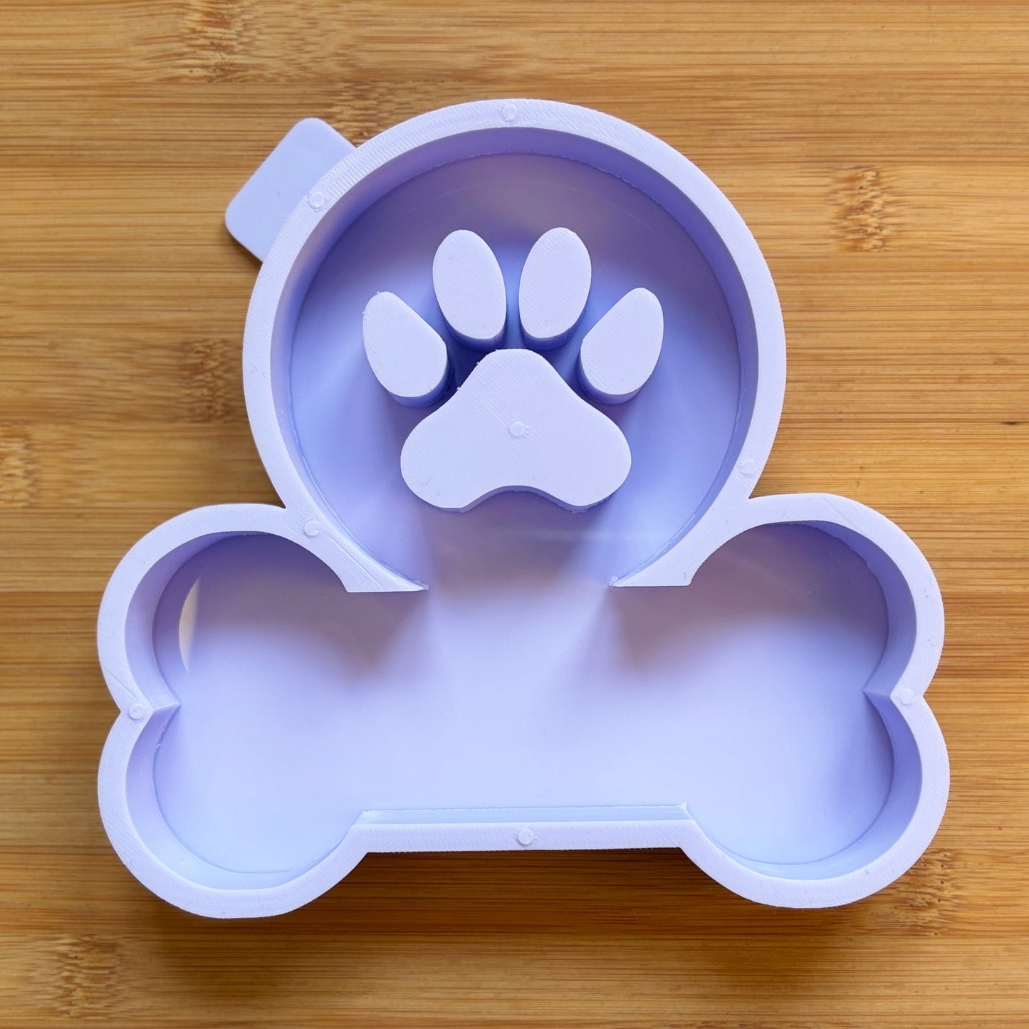 Purple silicone of a bone with a paw print design on a wooden surface