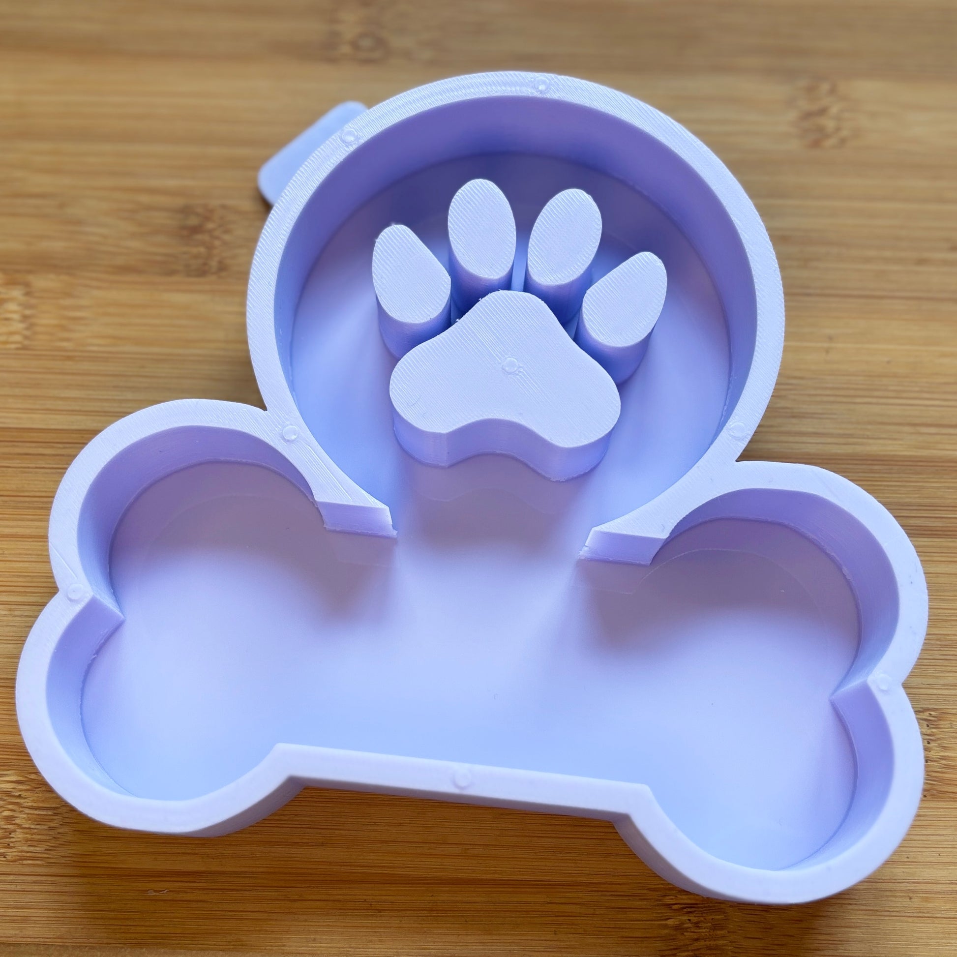 Silicone mold shaped like a bone with a paw print on a wooden surface