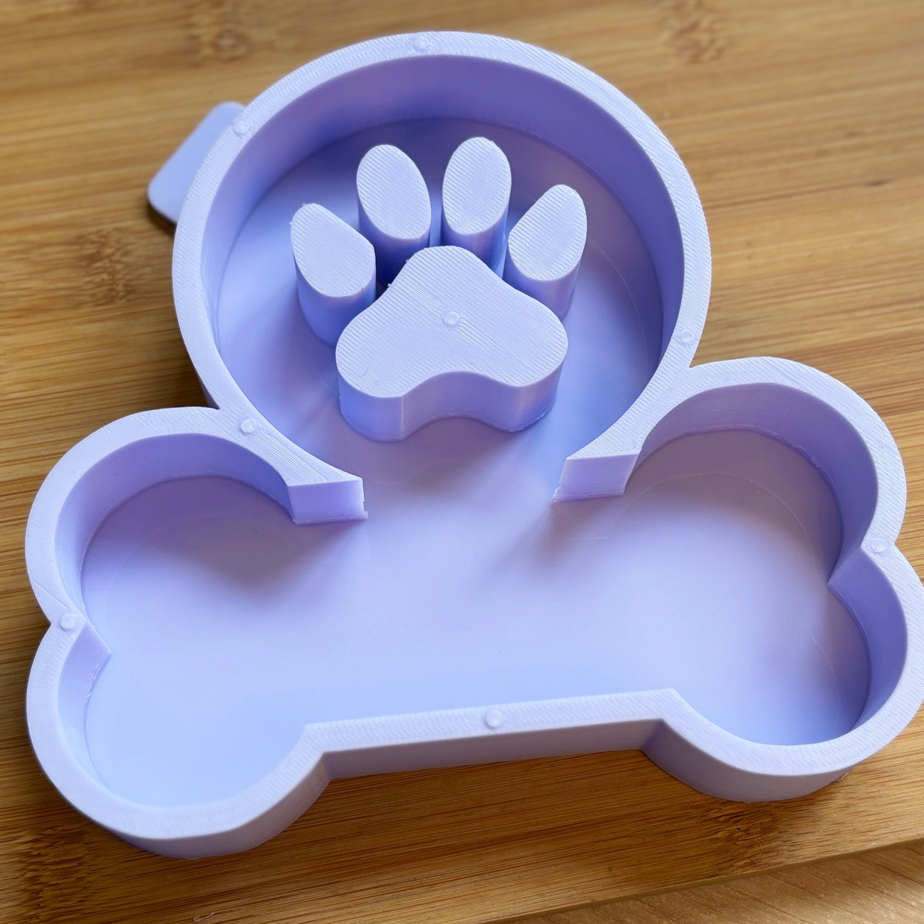 Silicone mold shaped like a dog bone and paw print on a wooden surface