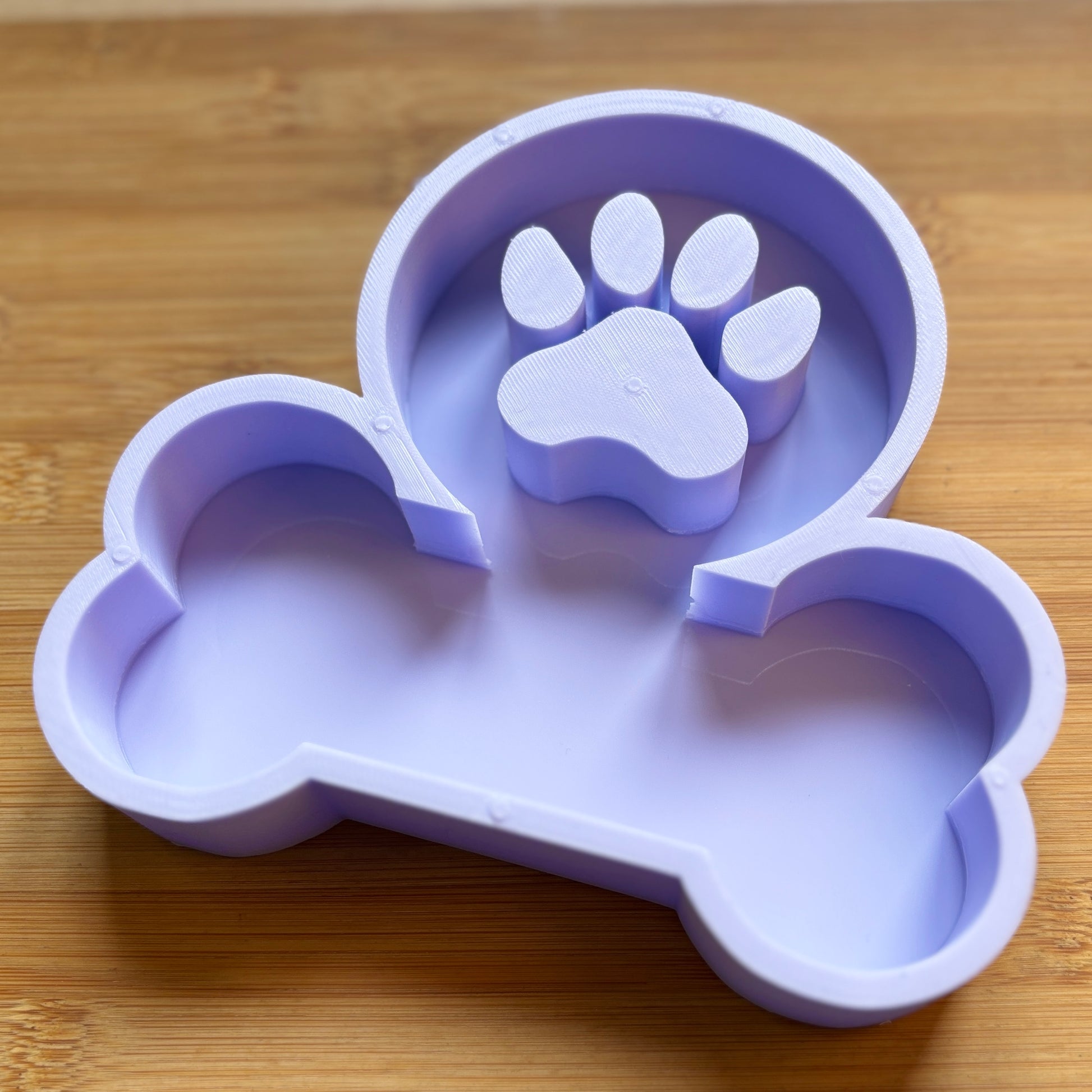 Silicone mold shaped like a dog bone with a paw print on a wooden surface