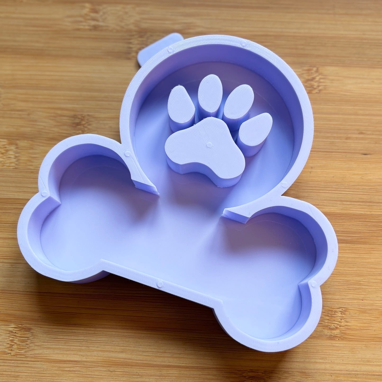 Silicone mold shaped like a dog bone with a paw print on a wooden surface