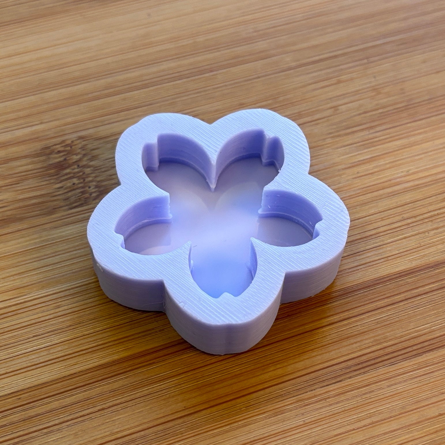 Flower-shaped purple silicone mold on a wooden surface