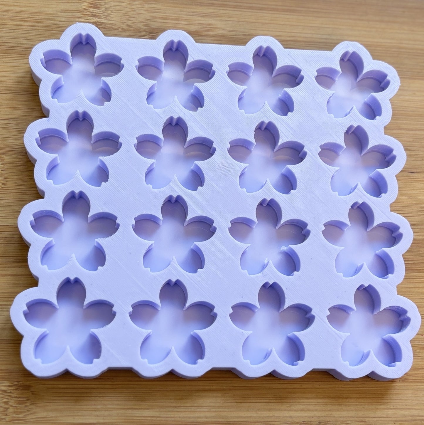 Silicone mold with flower-shaped cavities on a wooden surface