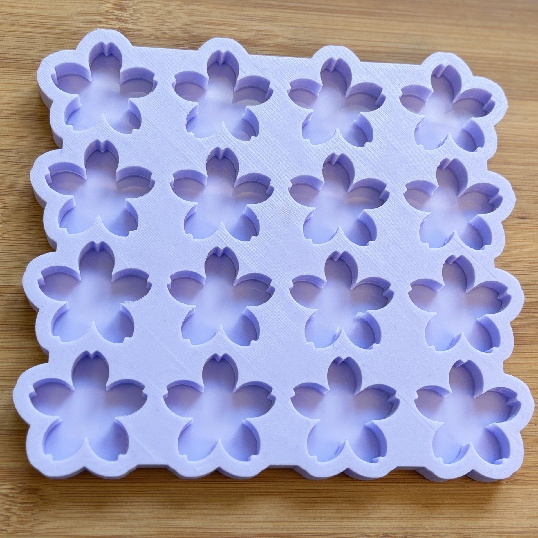Silicone mold with flower-shaped cavities on a wooden surface