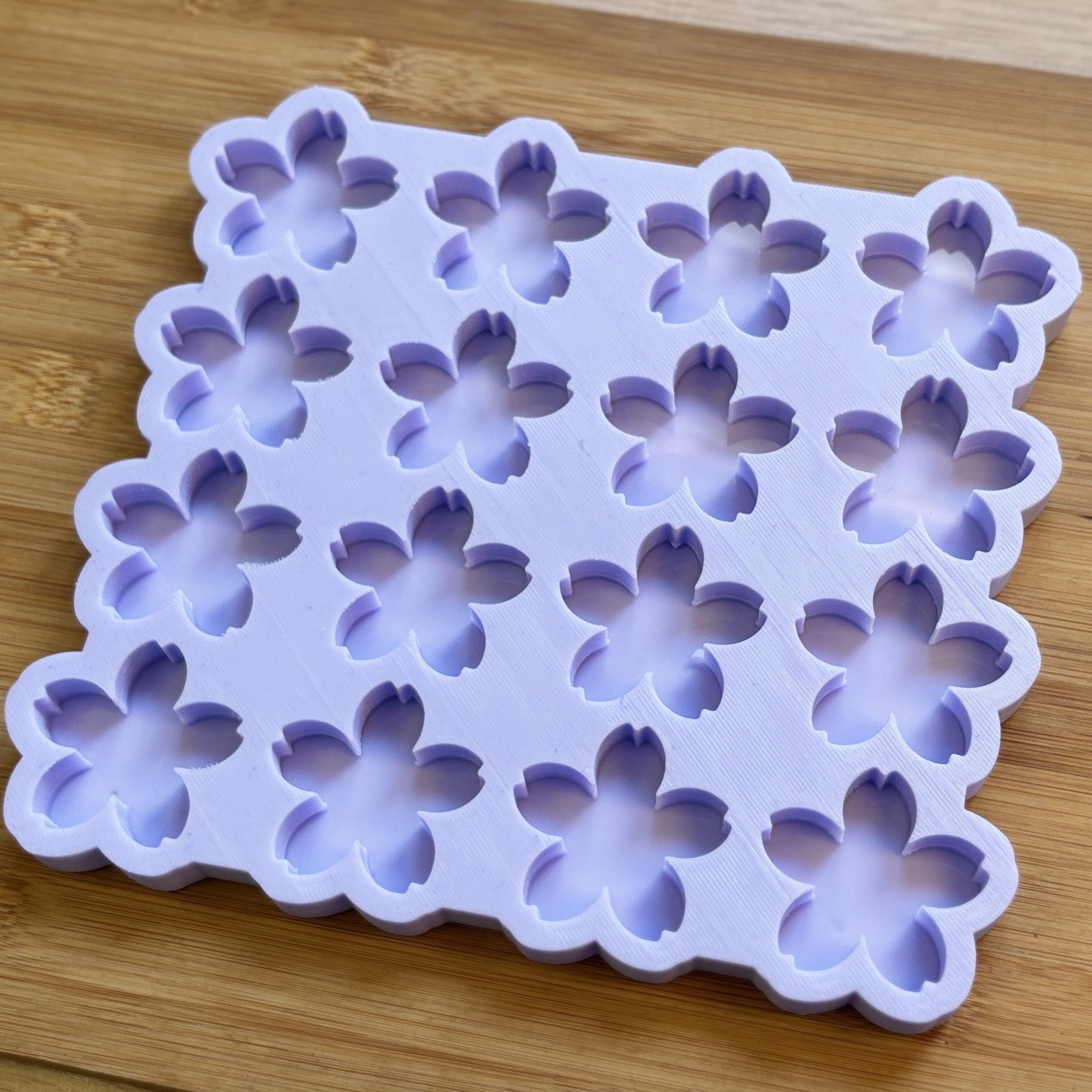 Silicone mold with flower-shaped cavities on a wooden surface