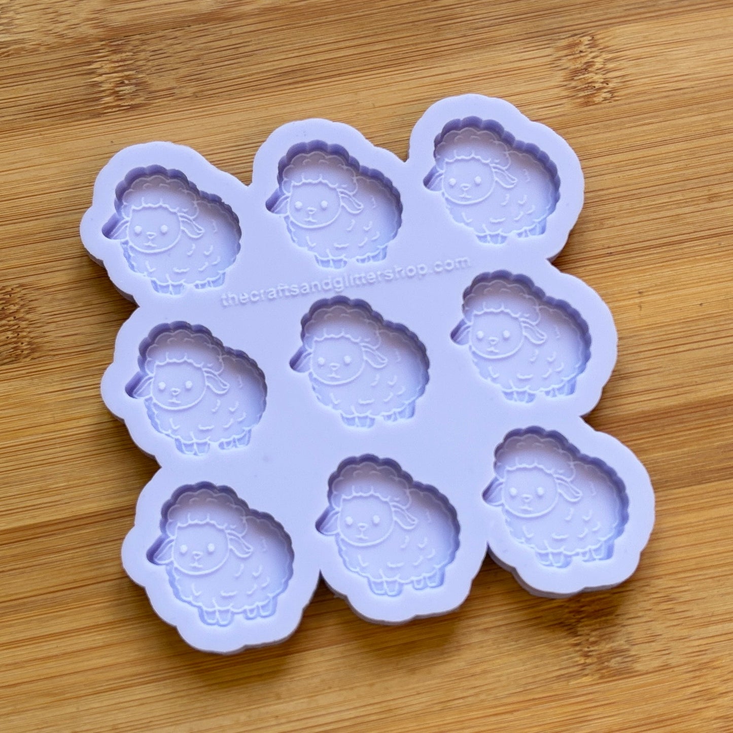 Purple silicone mold with sheep designs on a wooden surface