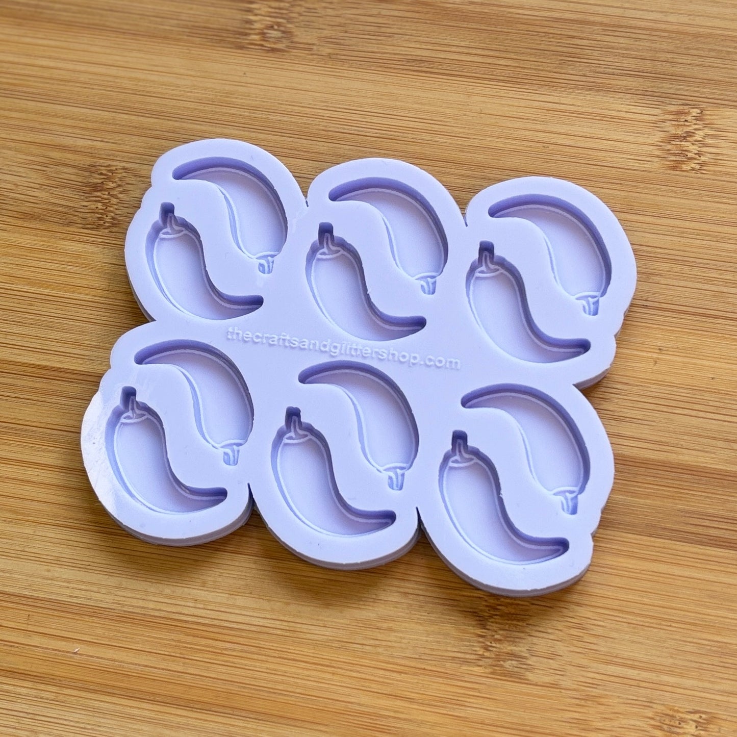 Purple silicone ice cube tray with chilli pepper molds on a wooden surface