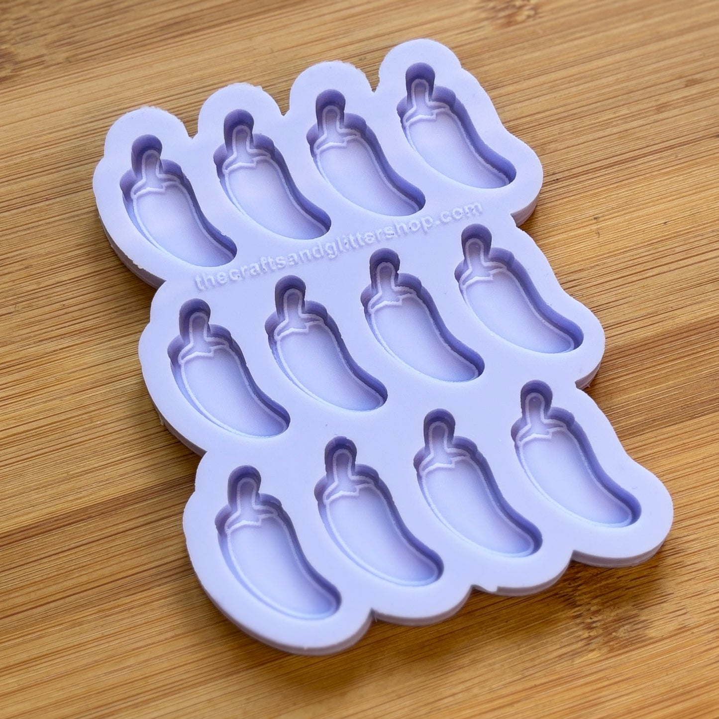 Purple silicone ice cube tray with jalapeno-shaped molds on a wooden surface