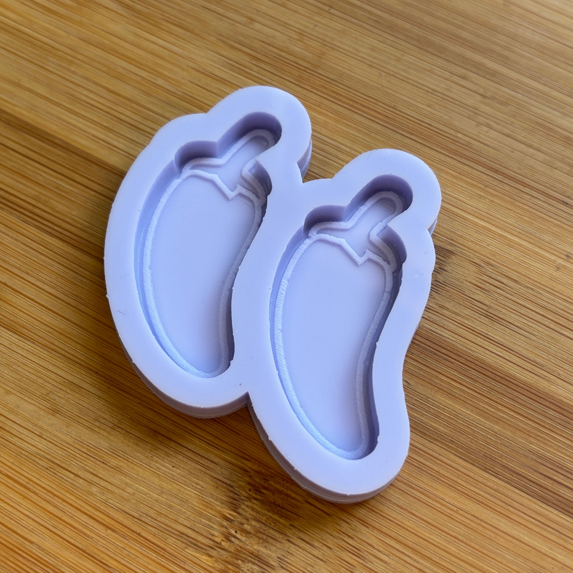 Silicone mold shaped like a chilli pepper on a wooden surface